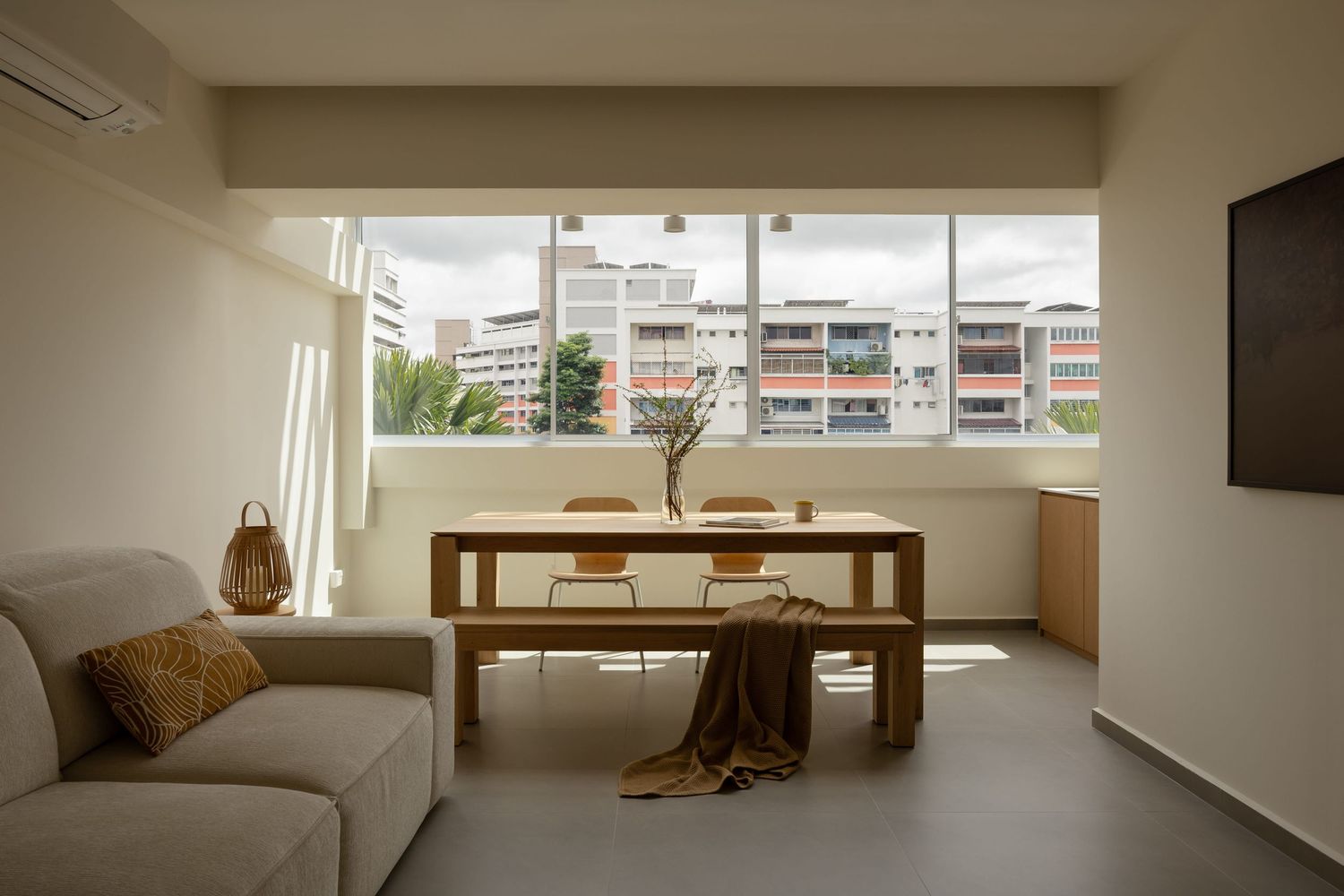 Modern minimalist apartment interior with white walls, large windows, and natural light creating a bright, open living space.