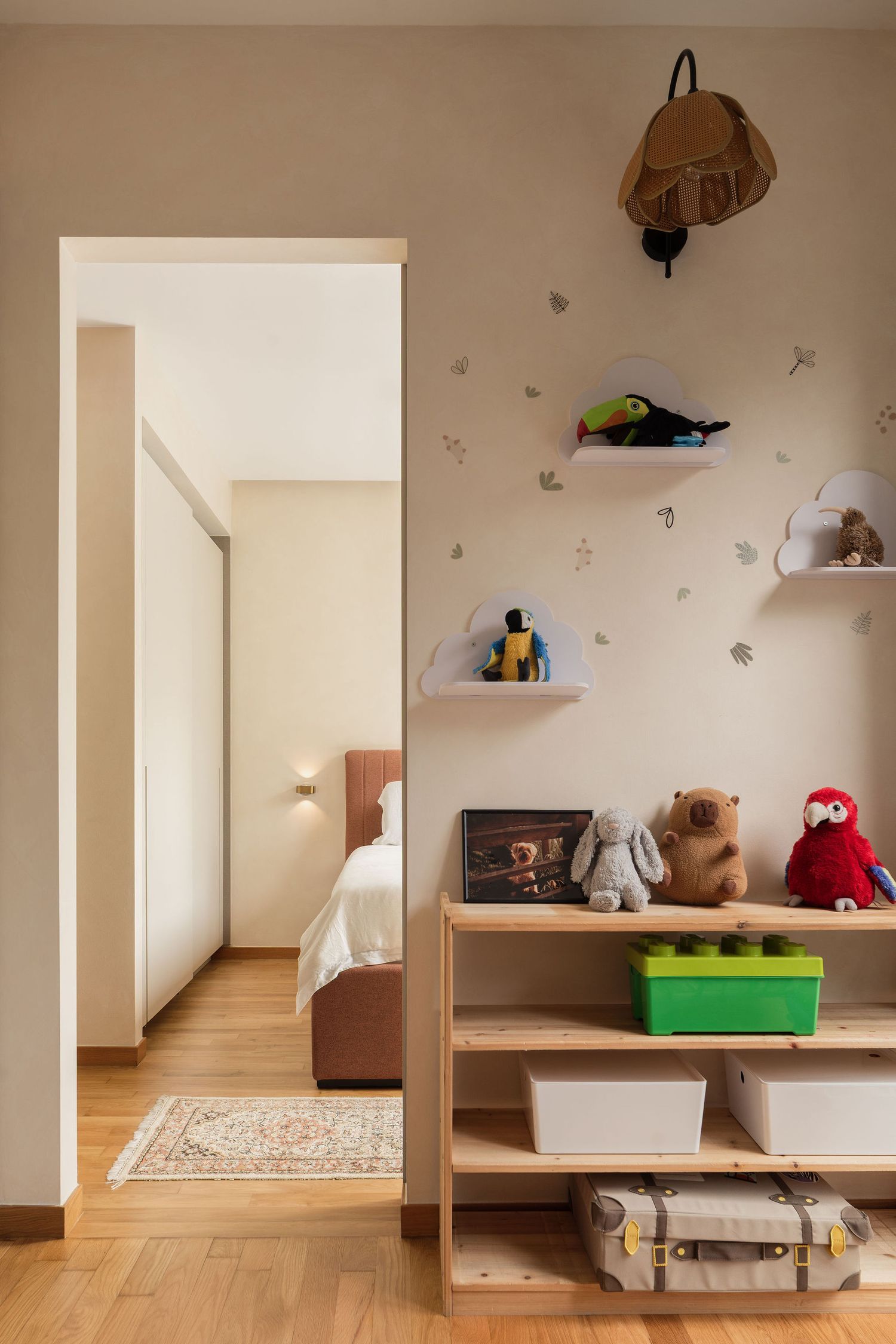 Child's bedroom with wooden shelves holding stuffed animals, cloud-shaped wall shelves, and a doorway leading to an adjacent room.