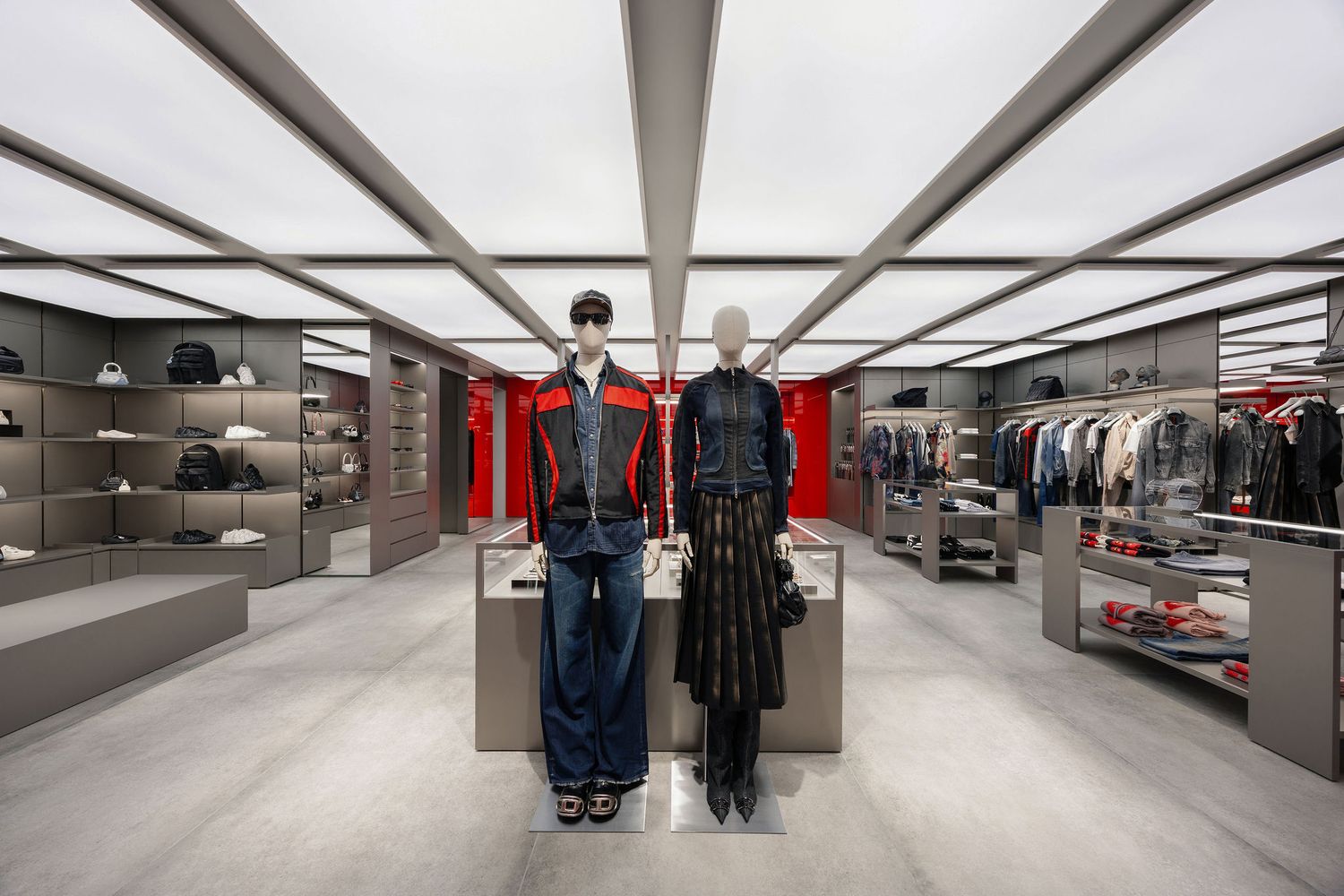Modern retail store interior with two mannequins displaying designer outfits, surrounded by shelves of accessories and clothing racks.