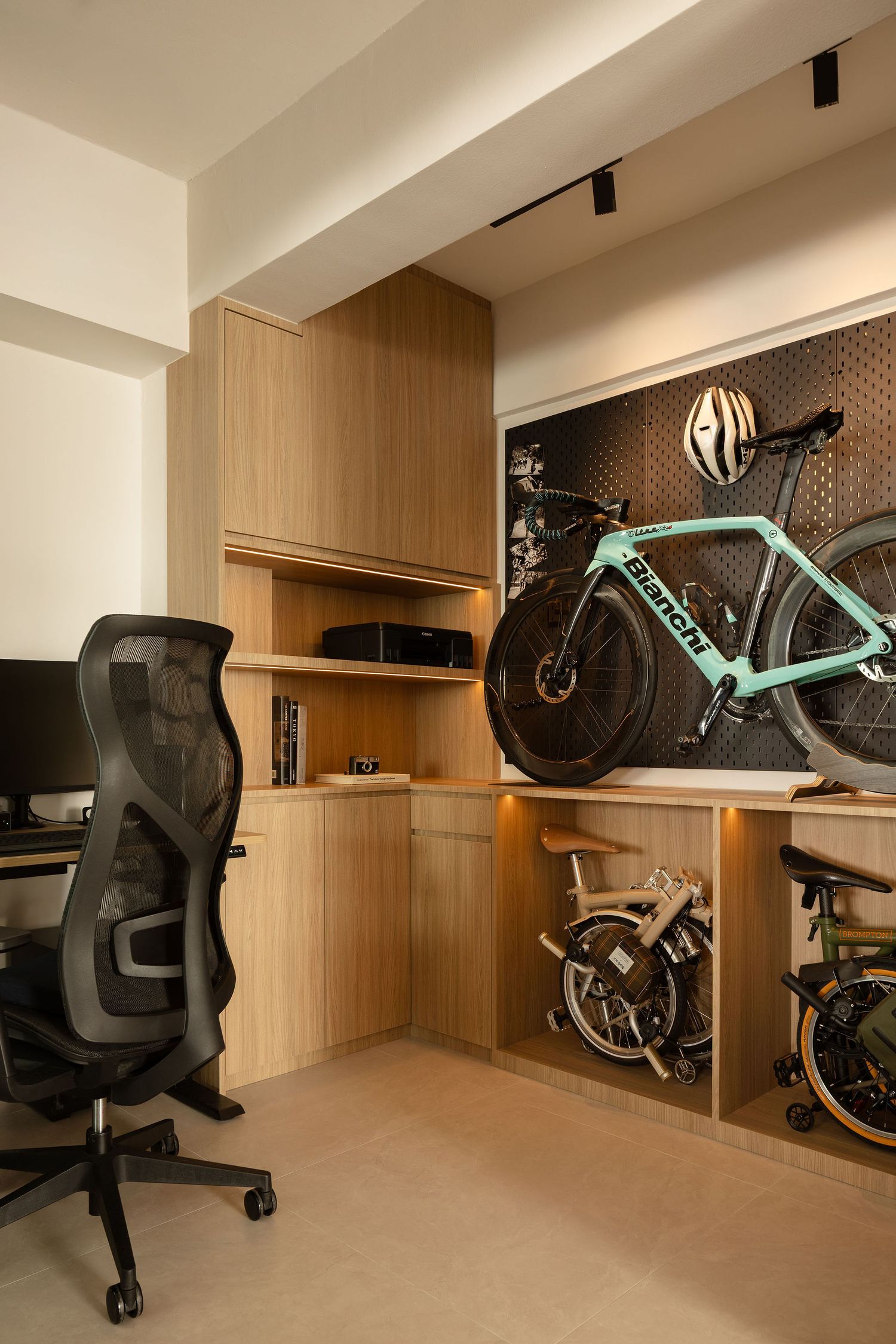 Modern home office with ergonomic chair, wooden built-in shelving, and a teal Bianchi bicycle mounted on a pegboard wall.