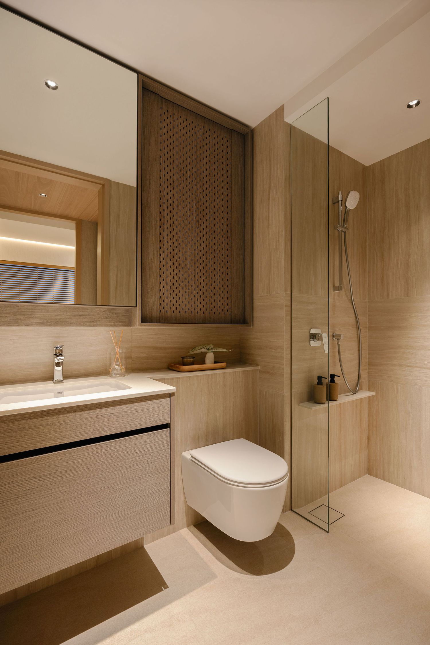 Modern bathroom with warm wood-look tiles, floating vanity with mirror, wall-mounted toilet and a glass-enclosed rainfall shower.