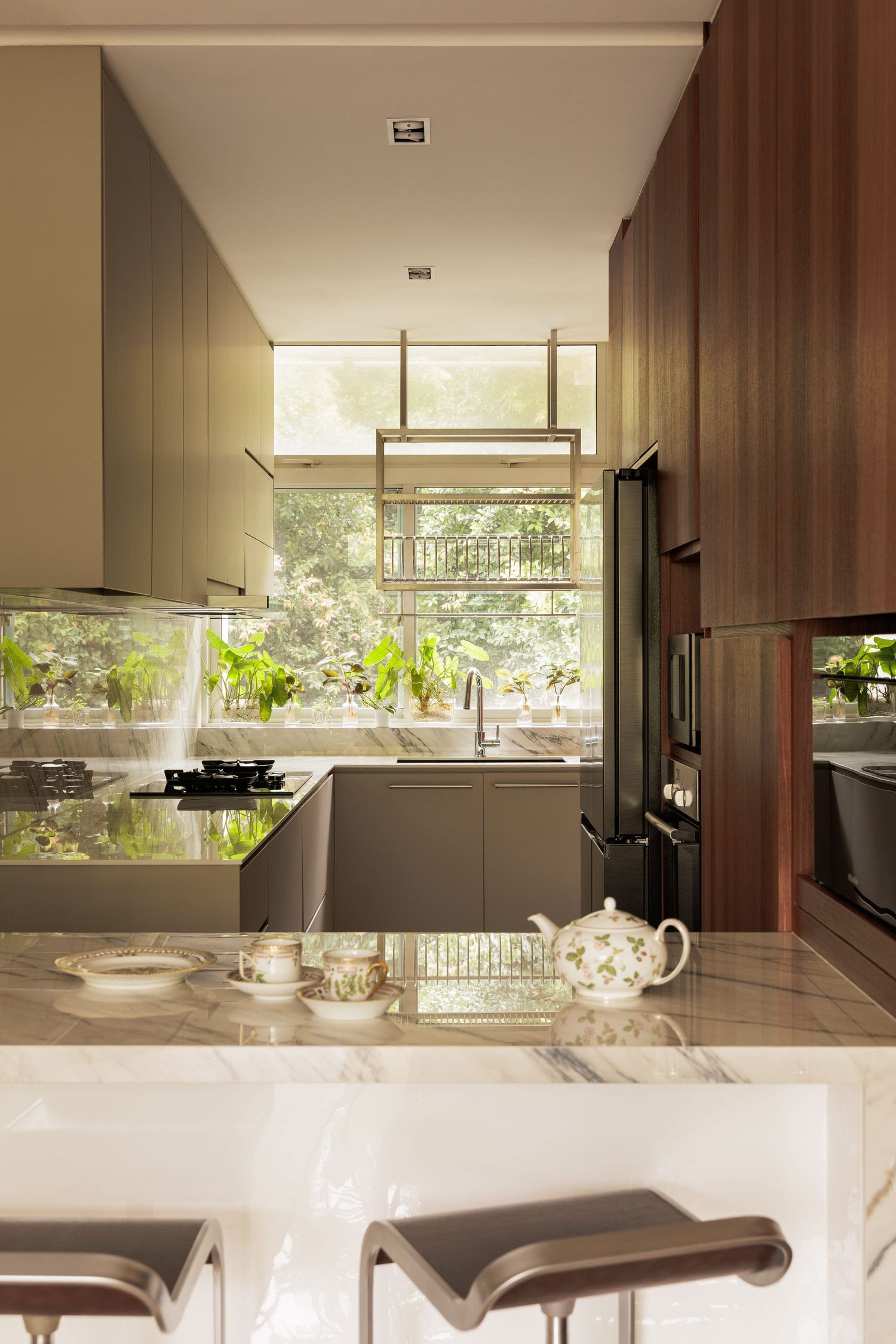 Modern kitchen interior with wooden accents, floor-to-ceiling windows, and natural light illuminating the countertop space.