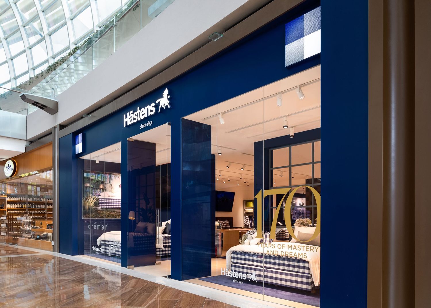 Hästens luxury mattress store with navy blue facade in a modern shopping mall interior.