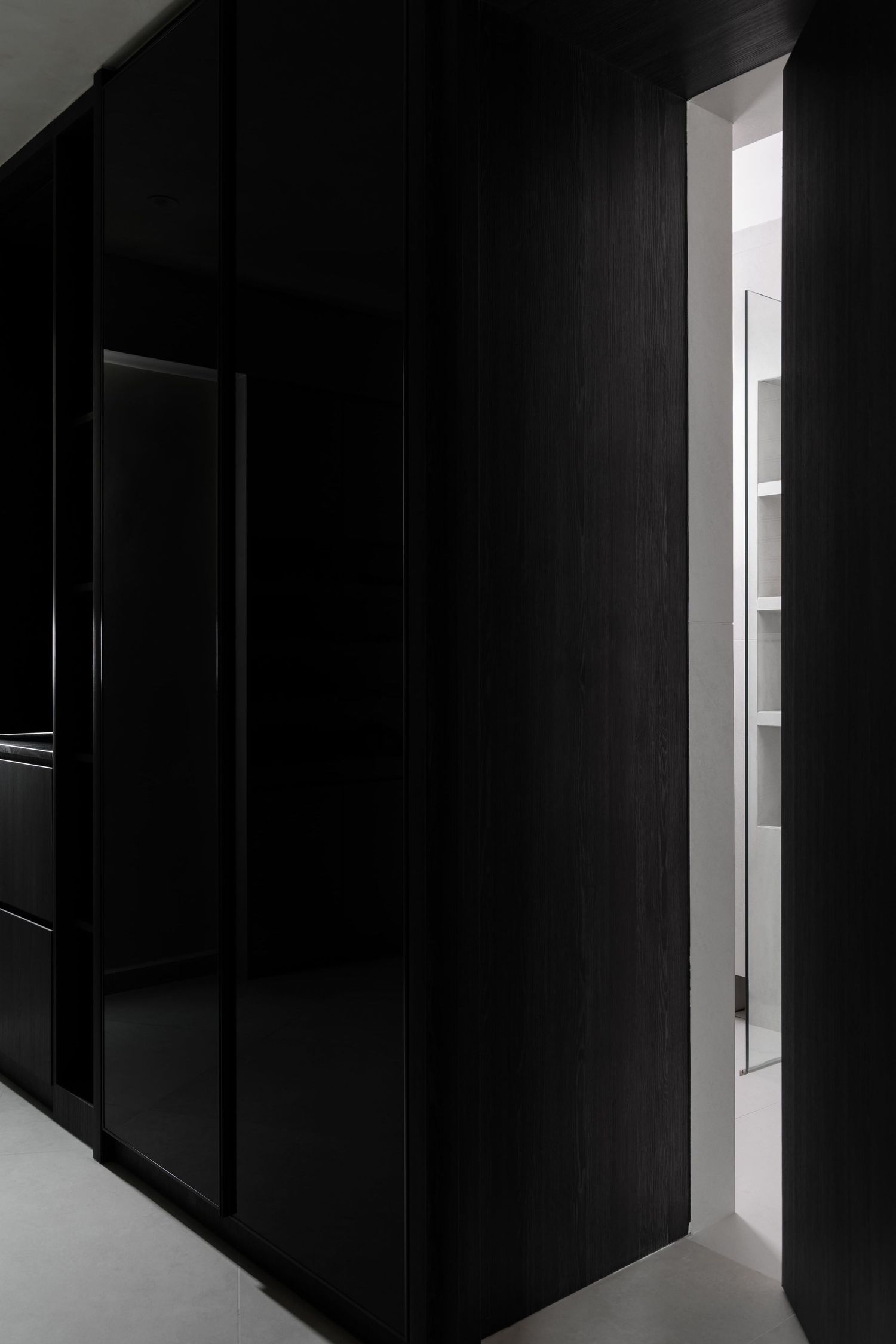 A dark modern hallway with black walls and bright white lighting creates a dramatic architectural contrast.