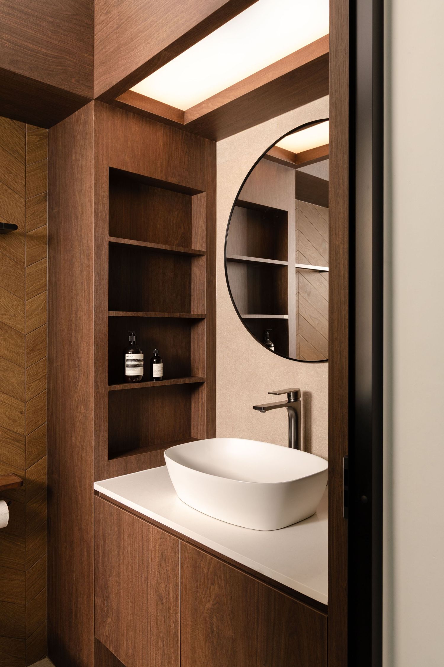 Modern bathroom interior with wooden walls and circular mirrors creating a sleek minimalist design aesthetic.