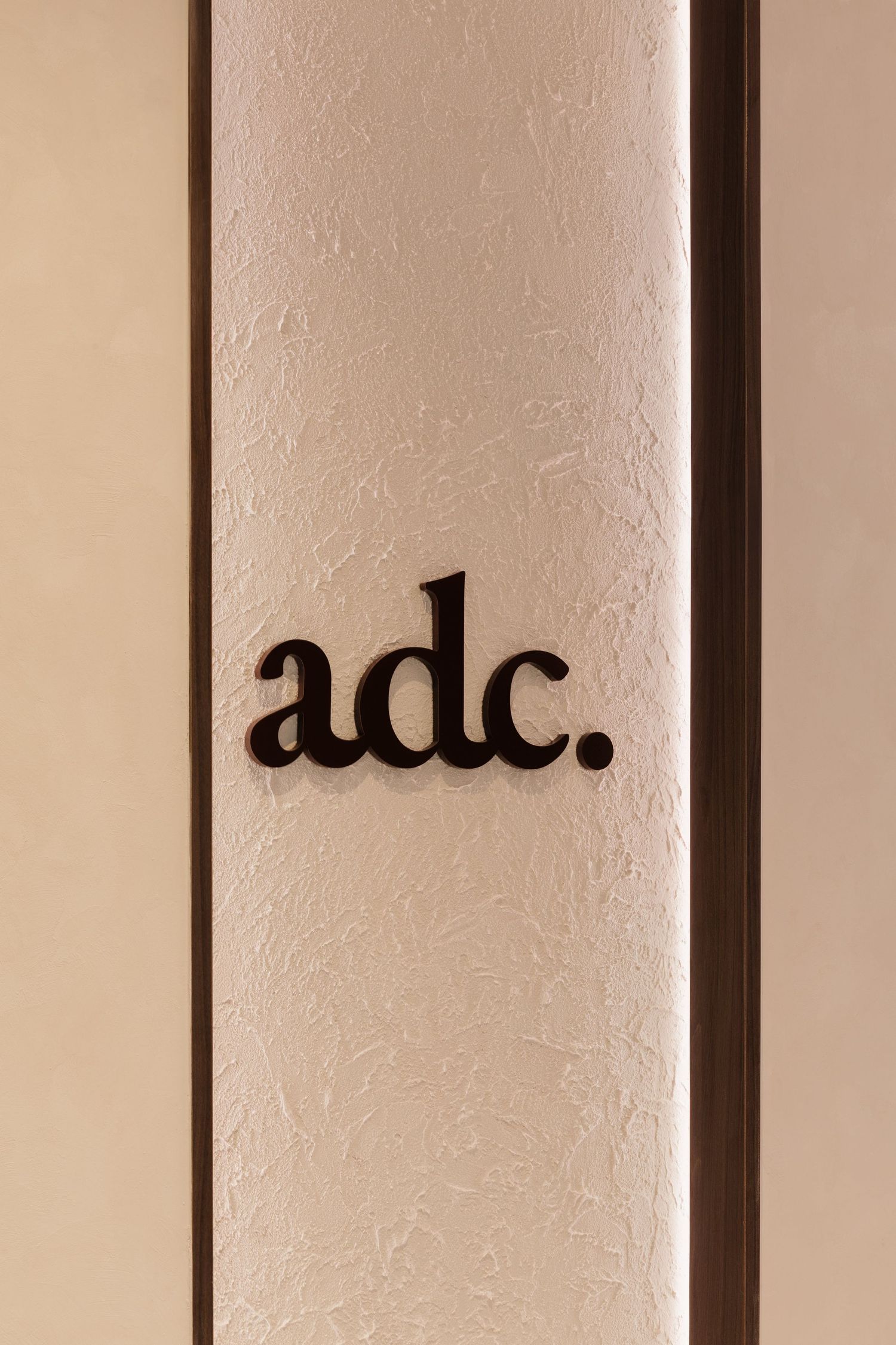 Closeup of black text fragments on a beige wall showing partial letters and typography details.