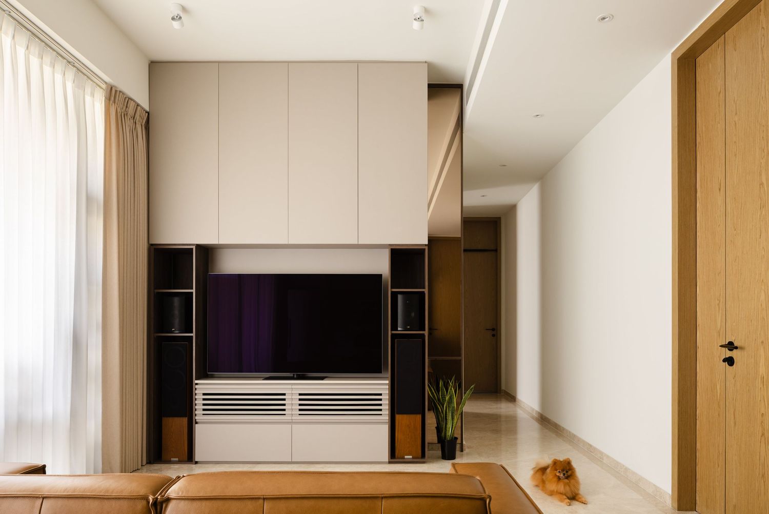 Modern living room interior with built-in entertainment unit featuring black panels and white storage cabinets.