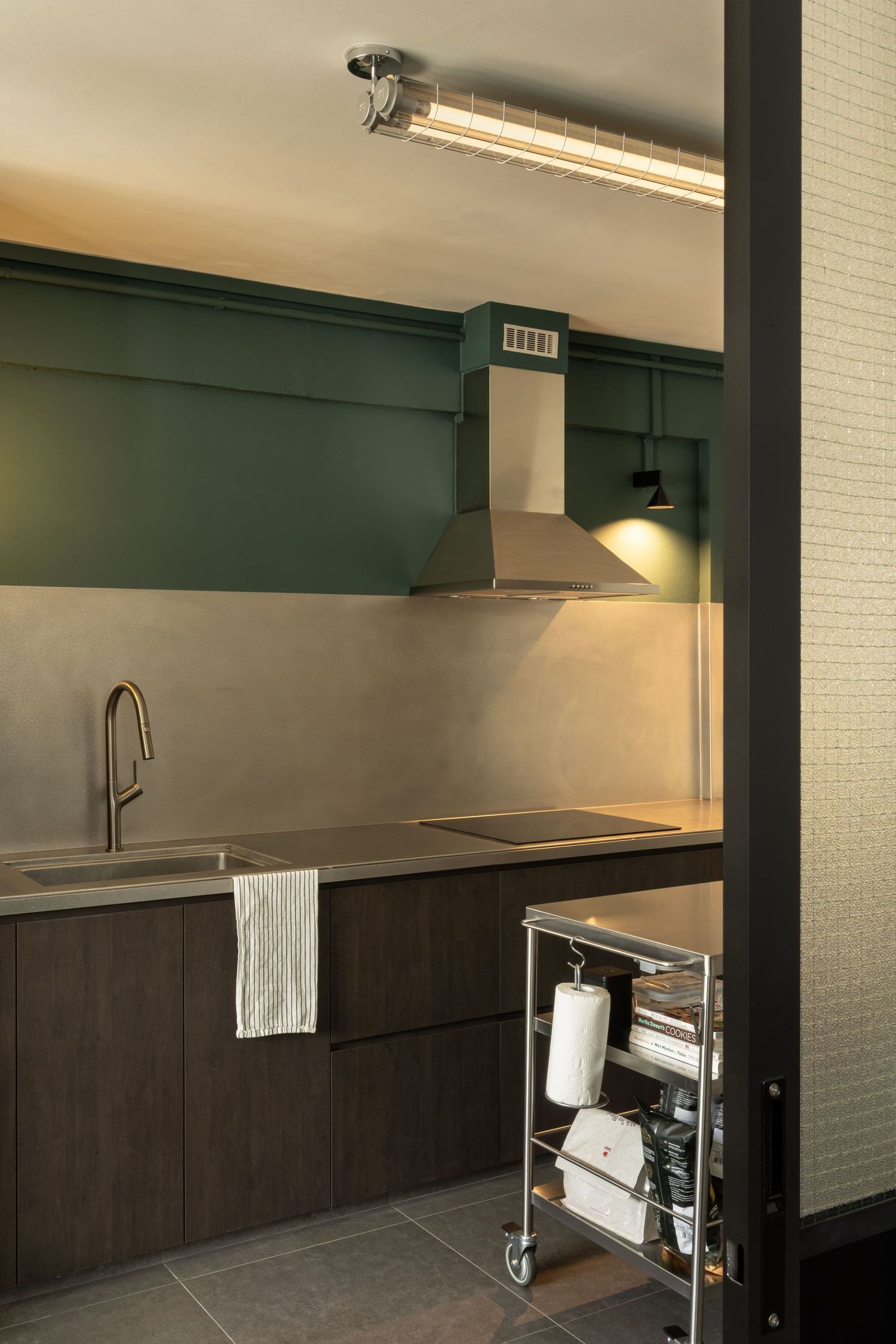 Modern dark wood kitchen cabinets with stainless steel appliances and white tile backsplash in contemporary interior space.