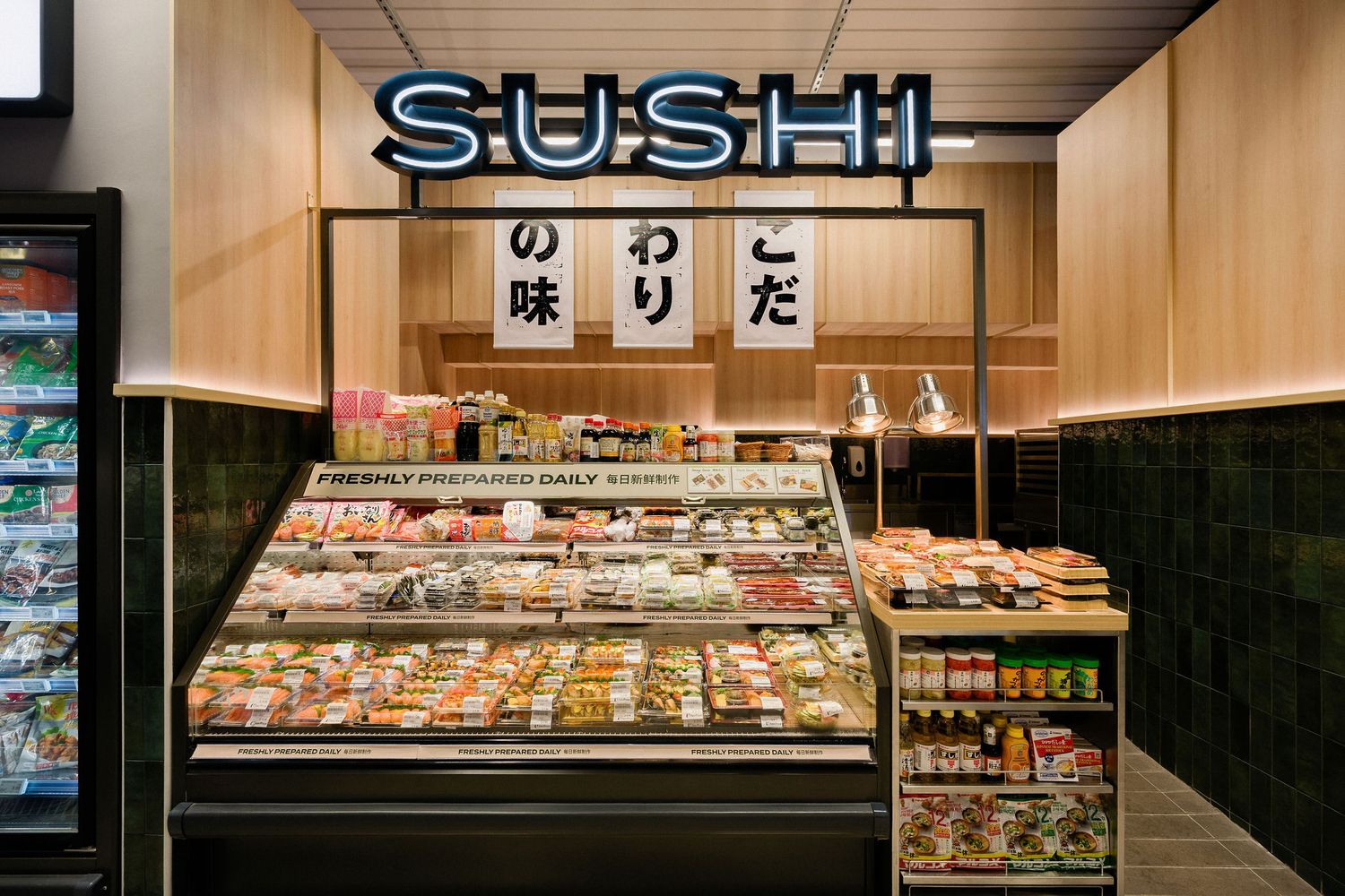 Modern sushi shop interior with a glowing neon SUSHI sign, refrigerated display case of freshly prepared sushi, and Japanese signage.