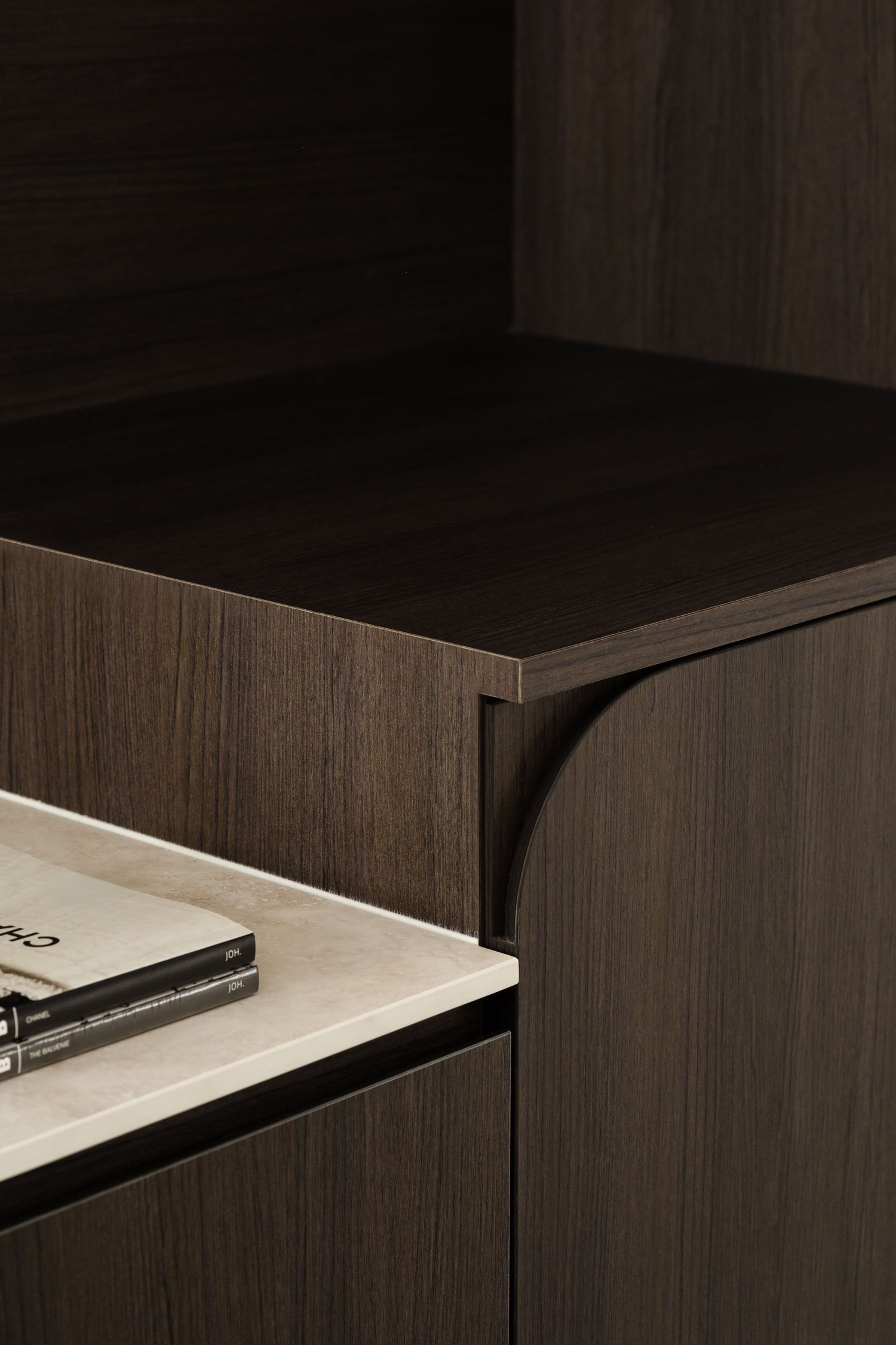 Modern dark wood furniture corner detail showing sleek minimalist design with contrasting surface textures.