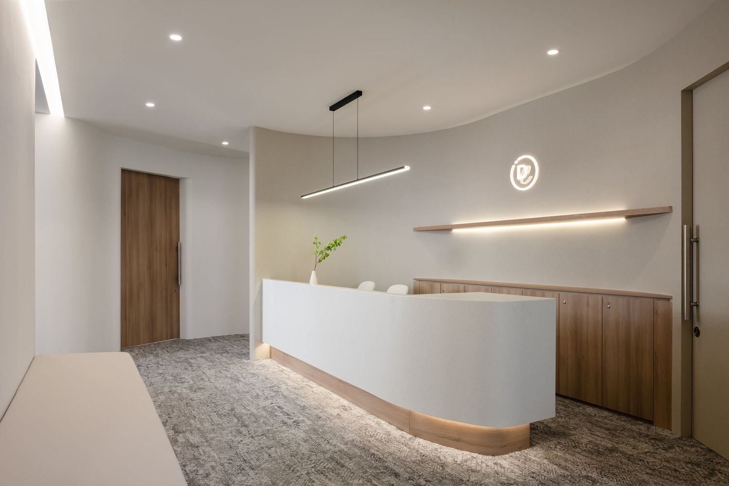 Modern minimalist interior with white walls and wood accent panels illuminated by recessed lighting in a hallway design.