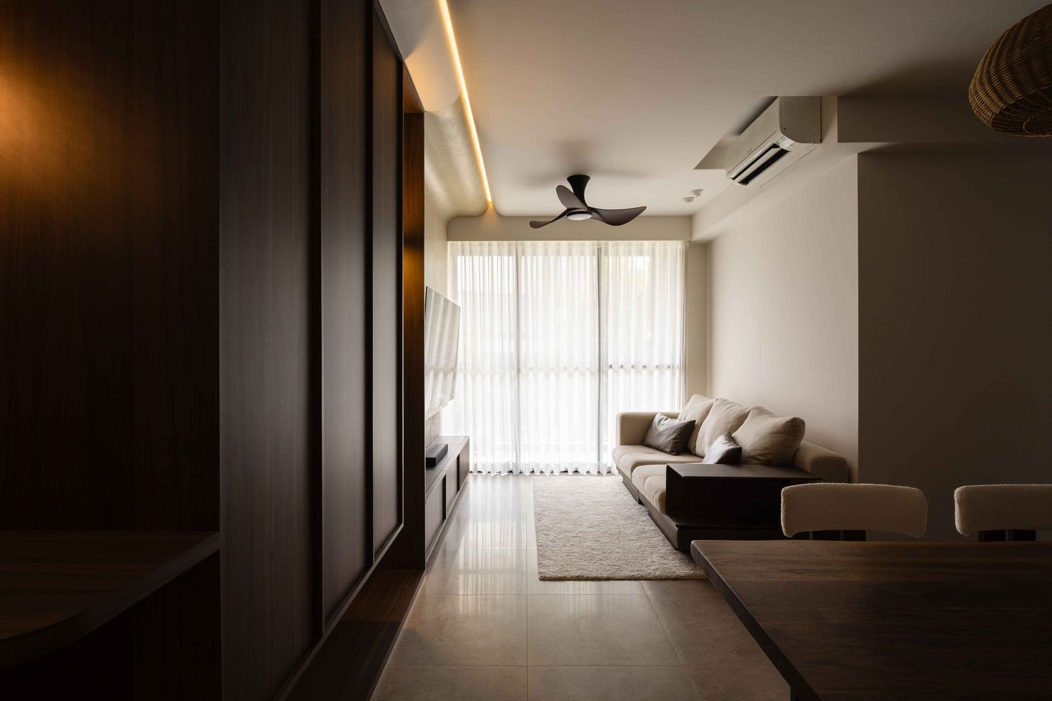 Modern minimalist living room interior with dark sofa, large windows, and moody ambient lighting.