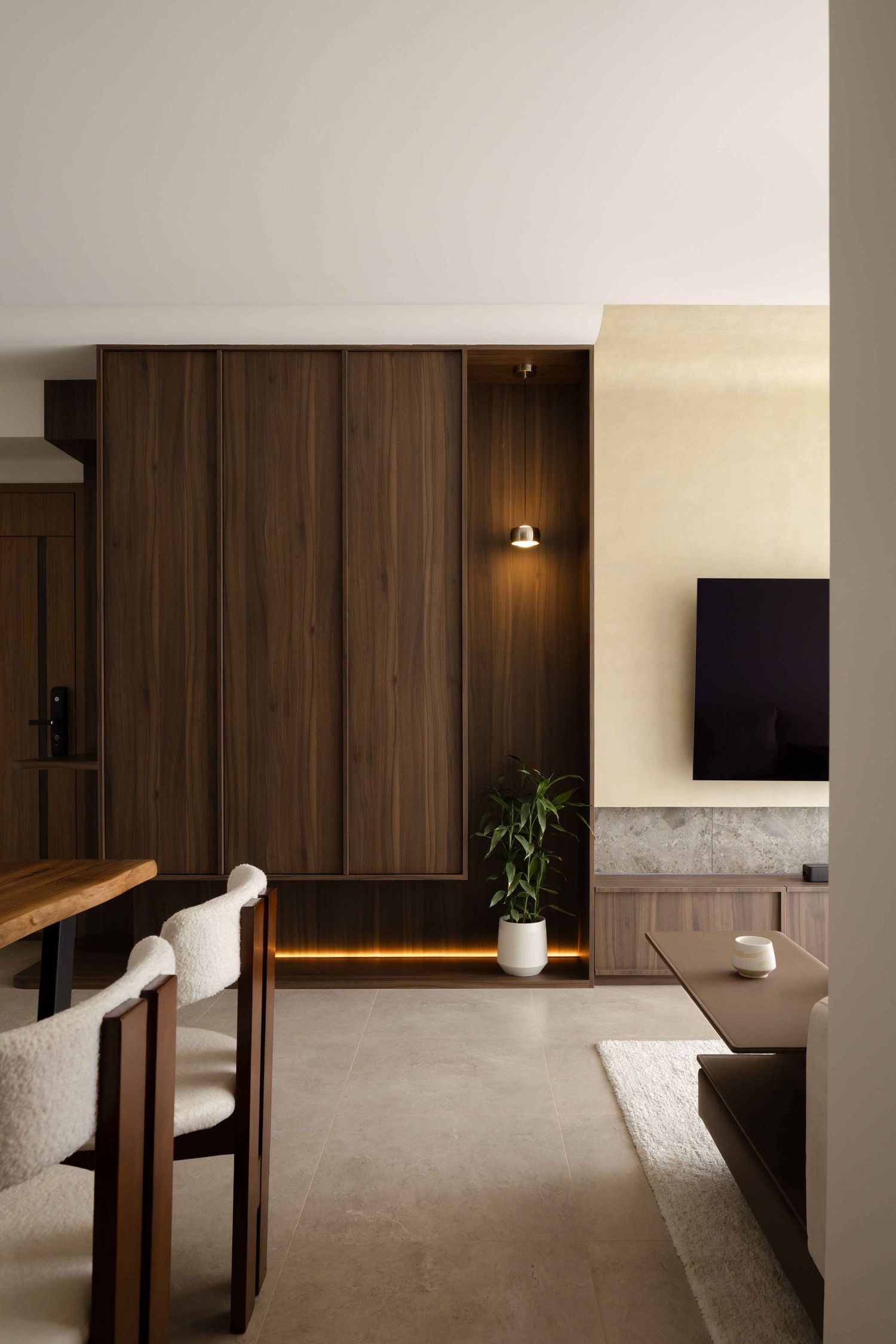 Modern minimalist living room with dark wood paneling, wall-mounted TV, and sleek furniture in neutral tones.