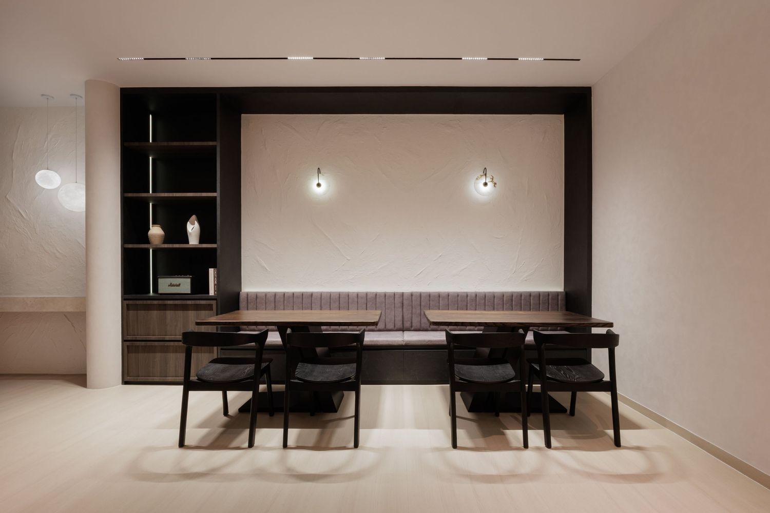 Modern minimalist dining room with black chairs and pendant lighting in a neutral color scheme.