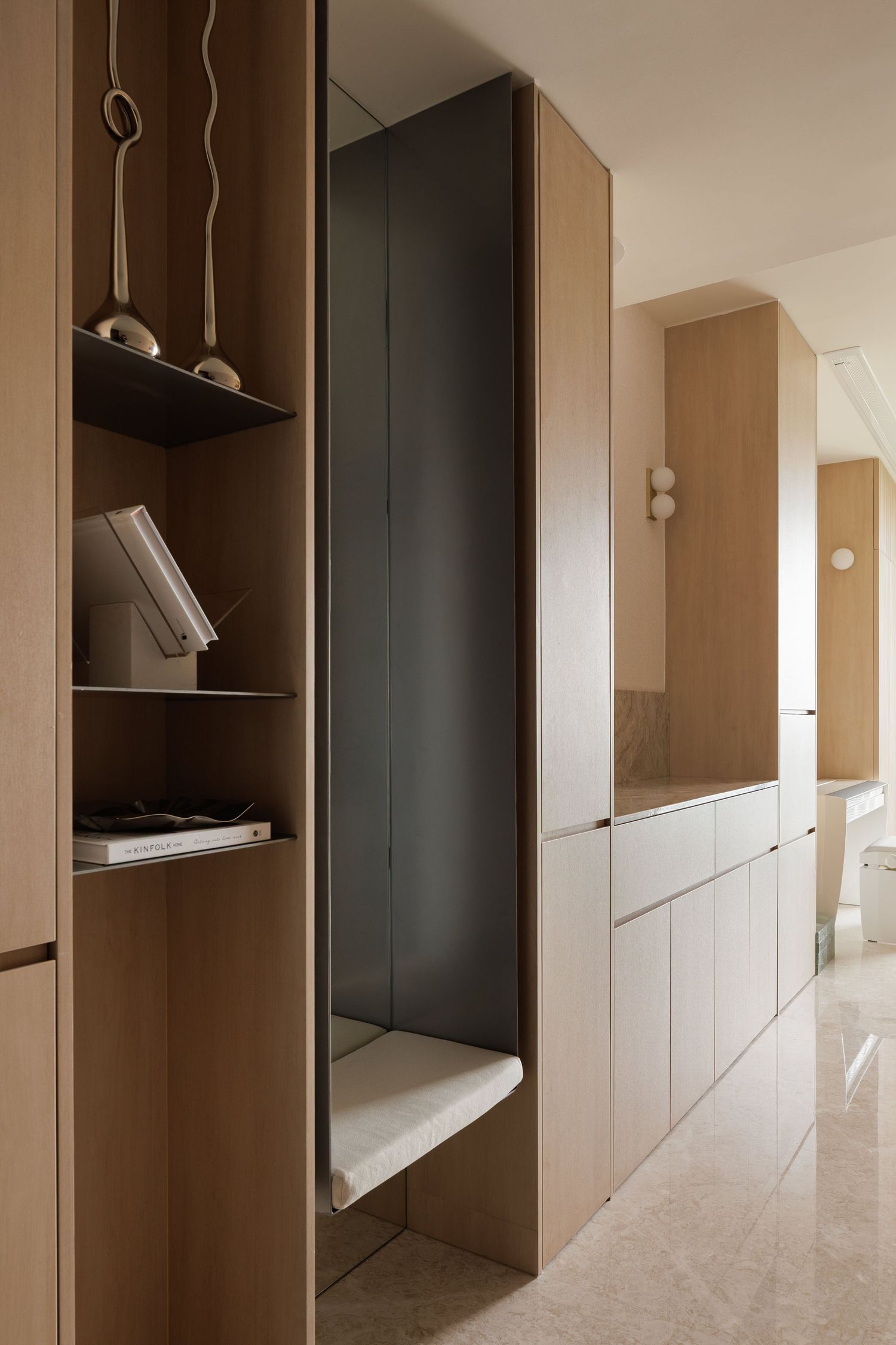 Modern built-in storage hallway with light wood cabinets, bookshelves and a hidden nook featuring sleek minimal design.