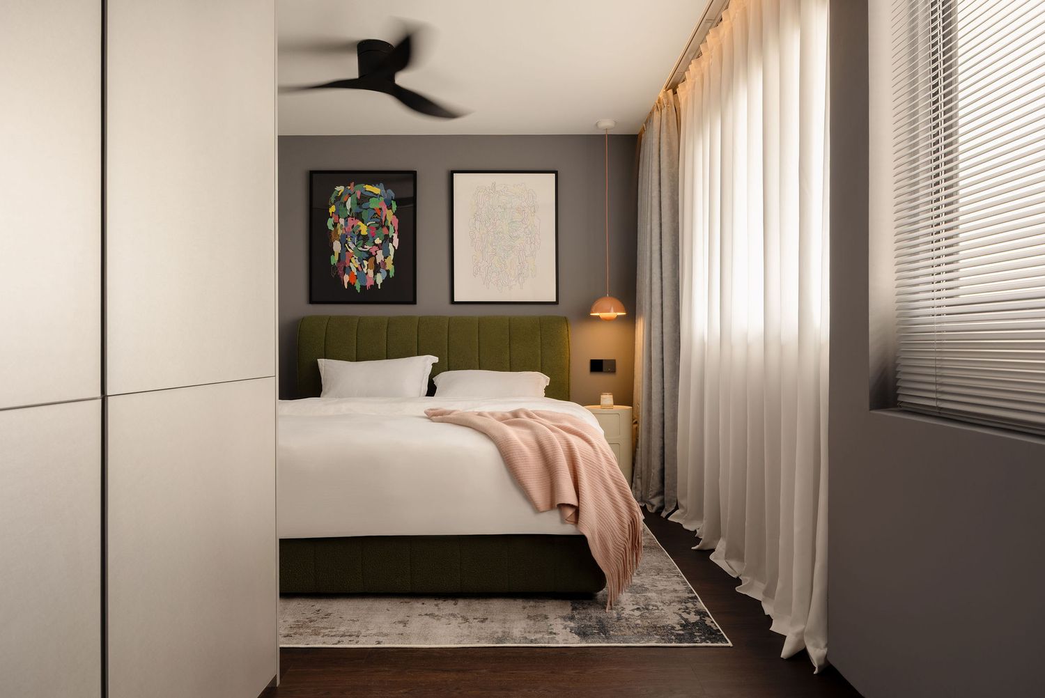 Modern bedroom with green upholstered bed, colorful wall art, sheer curtains, ceiling fan, and warm wood accents.
