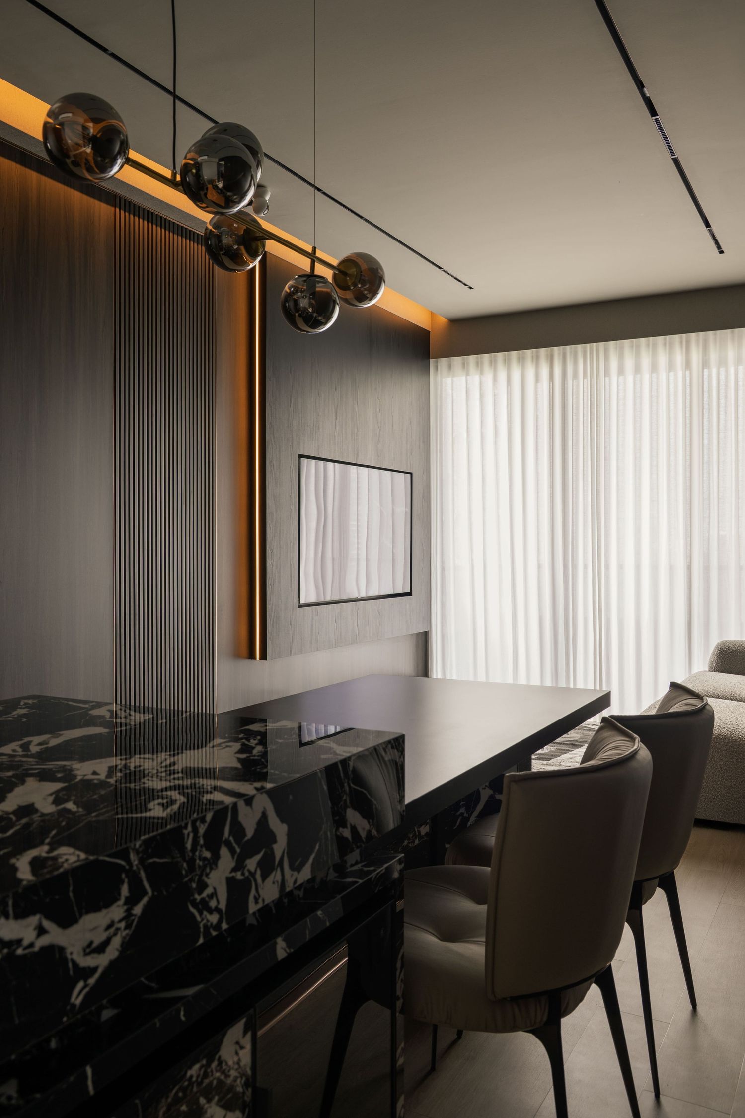 Modern dining room with black marble table, globe pendant lights, and floor-to-ceiling sheer curtains with warm accent lighting.