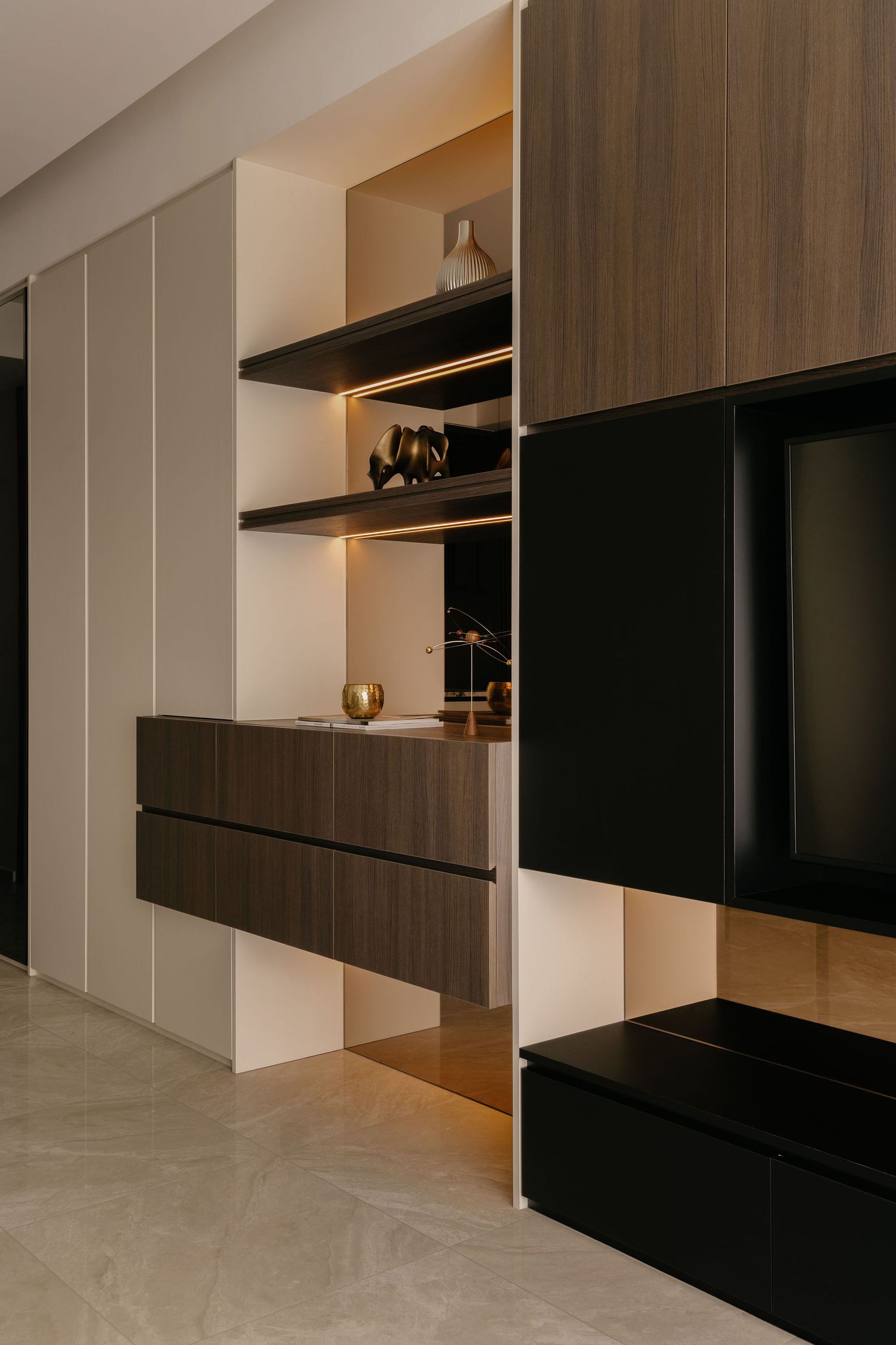 Modern living room storage unit with walnut wood drawers, white cabinets, LED-lit floating shelves, decor accents and a black TV console.