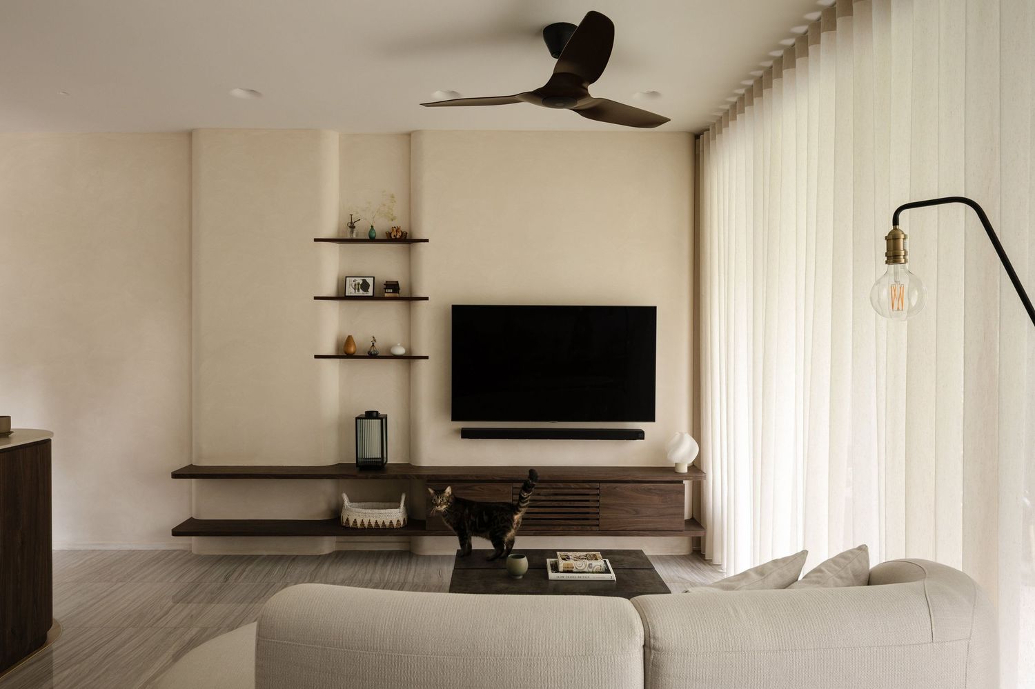 Modern open concept home interior with ceiling fan and cream walls in natural lighting.