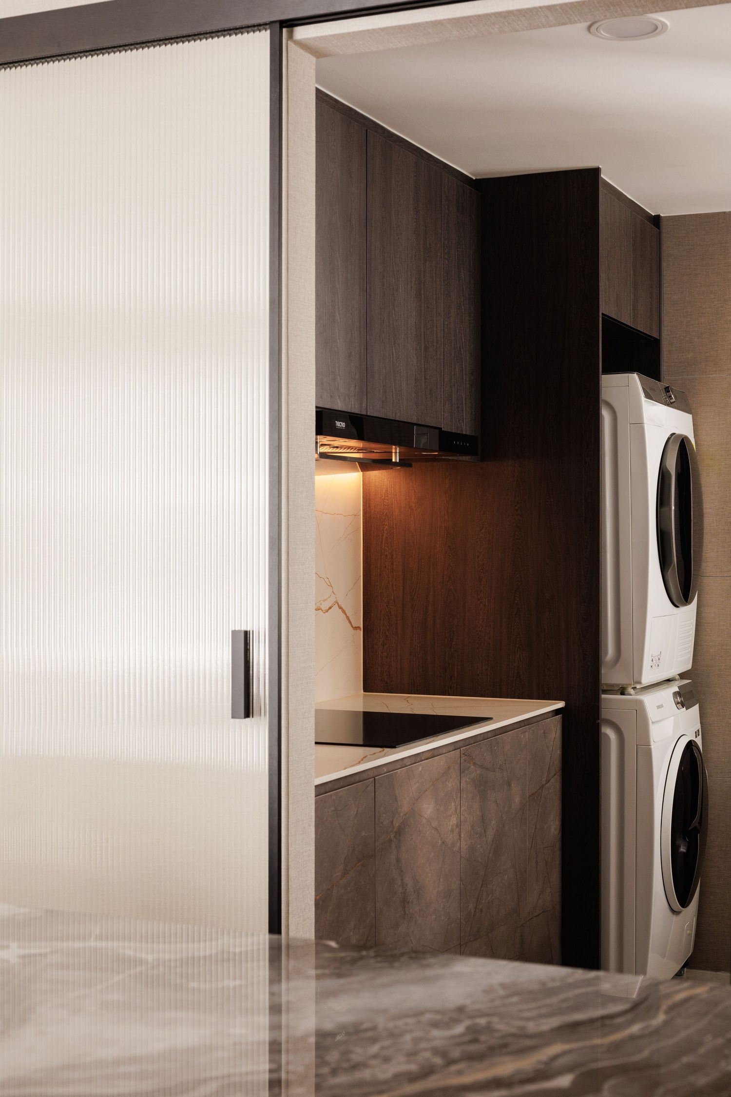 Modern laundry room interior with stacked washer and dryer units integrated into sleek wood cabinetry design.
