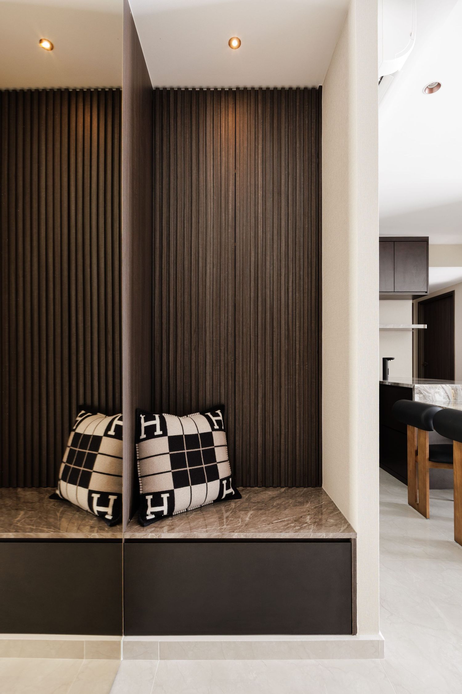 Modern interior with dark wood paneling, built-in bench seating, and geometric black and white throw pillows.
