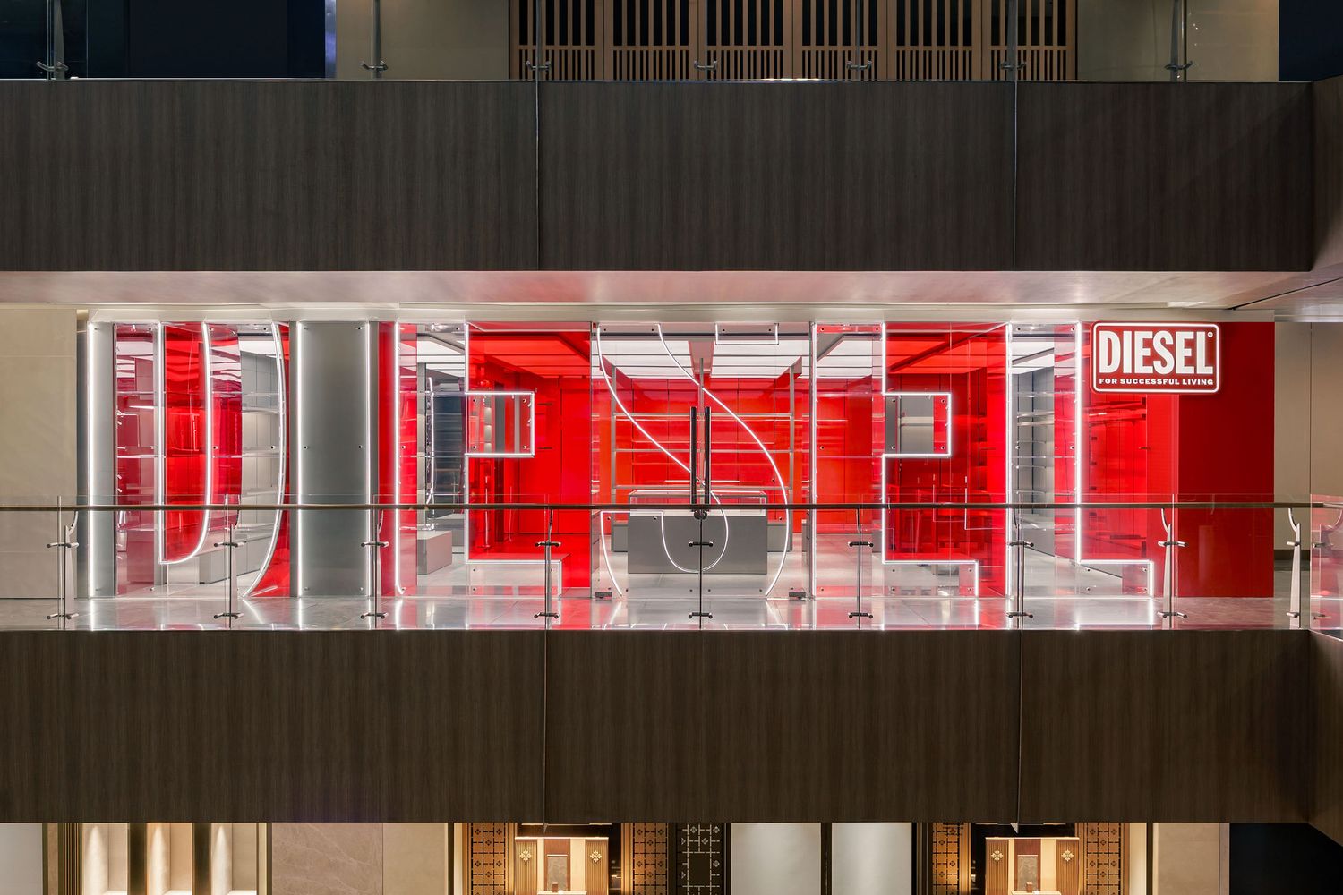 Diesel store illuminated in bold red with glass facade and iconic brand logo displayed at night.
