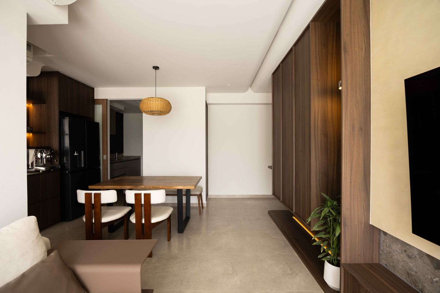 Modern minimalist dining room with wood paneling, pendant light, and concrete floors in a contemporary apartment interior.