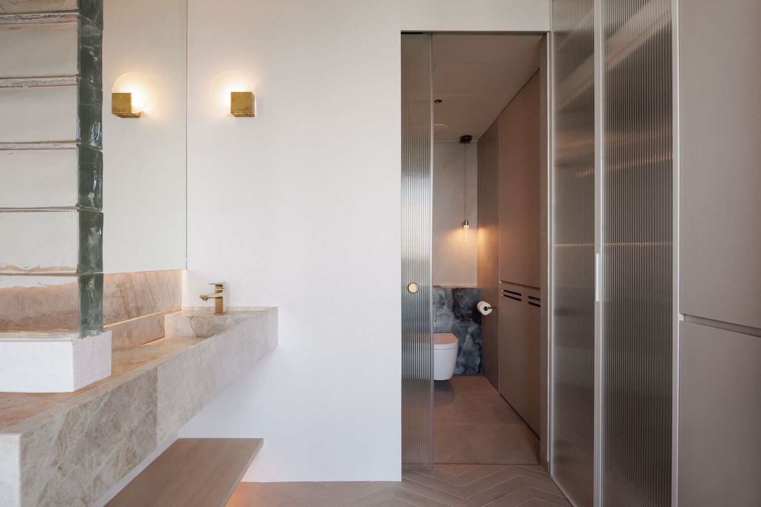 Modern apartment hallway with white walls, recessed lighting and tiled floors continues down a minimalist corridor.