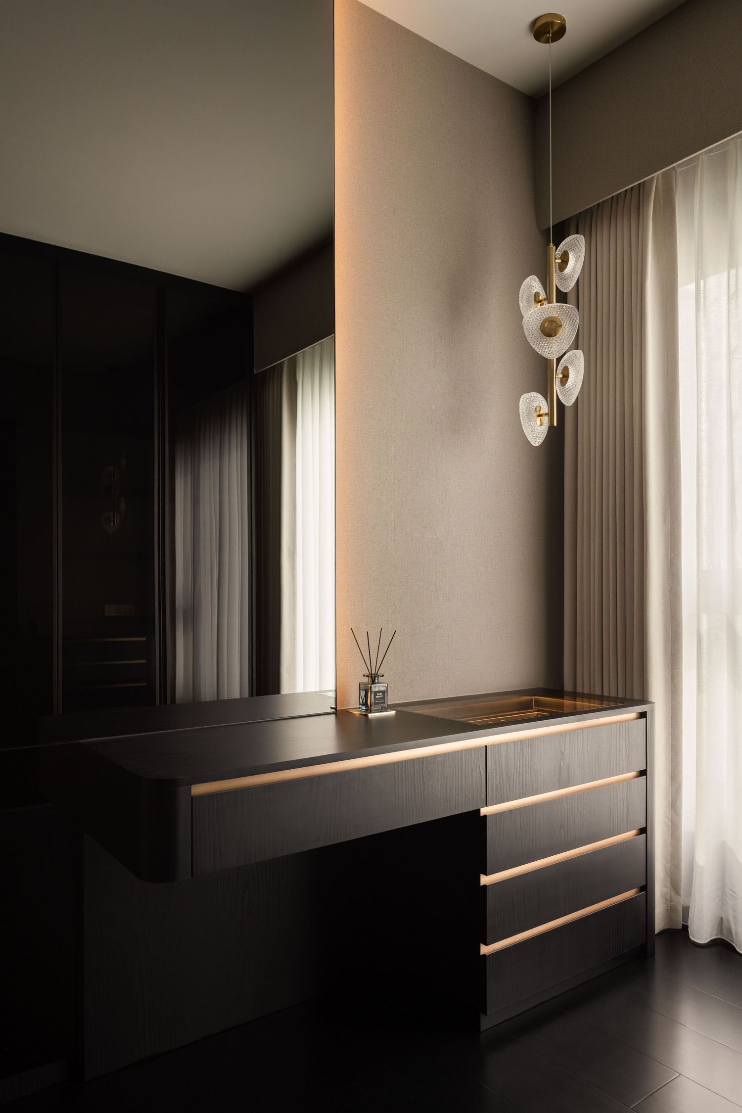 Sleek dark dresser with gold accents, modern pendant light, and sheer curtains in a luxury bedroom interior.
