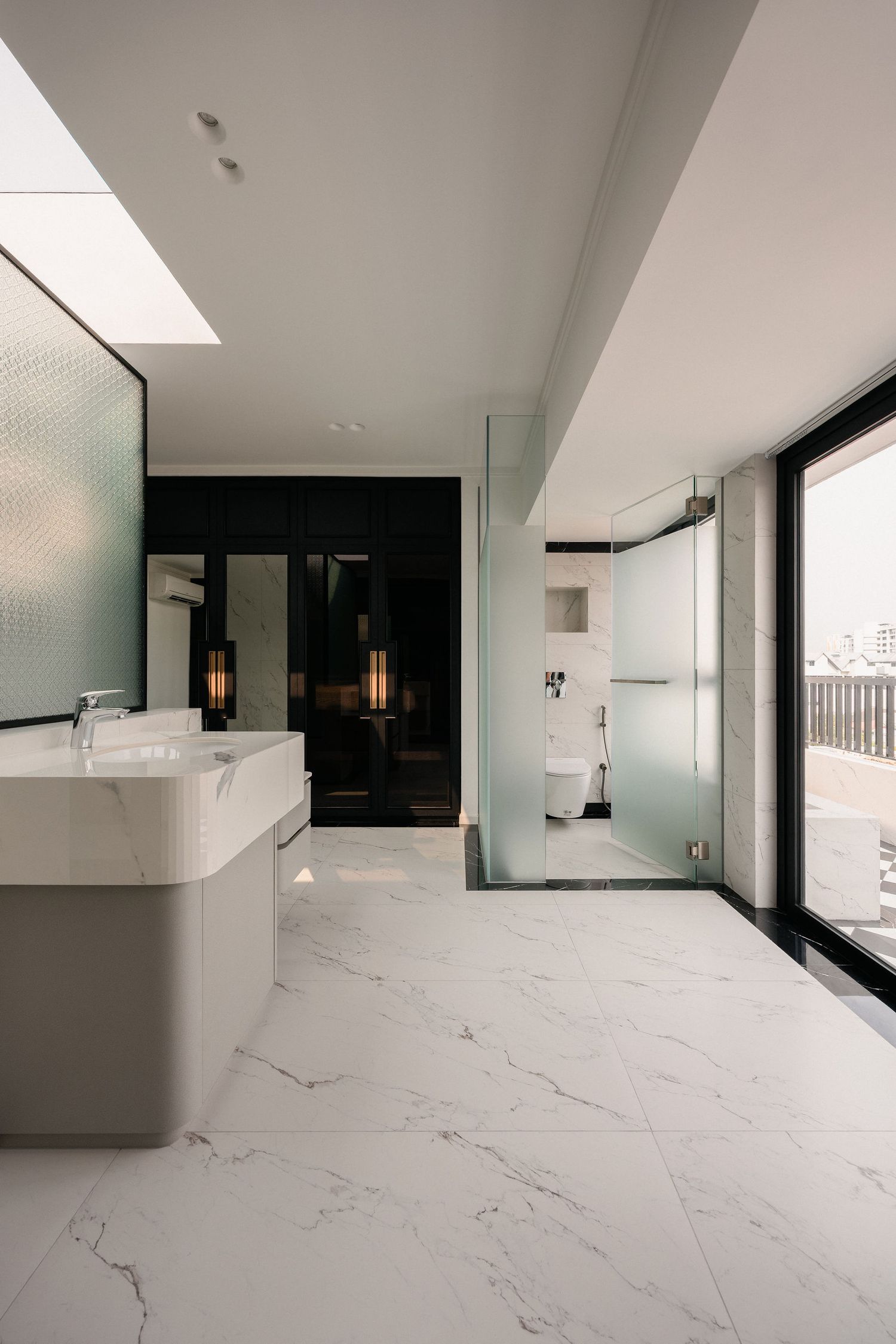Modern luxury bathroom with white marble flooring, floating vanity, frosted glass shower enclosure, skylight and a balcony view through floo