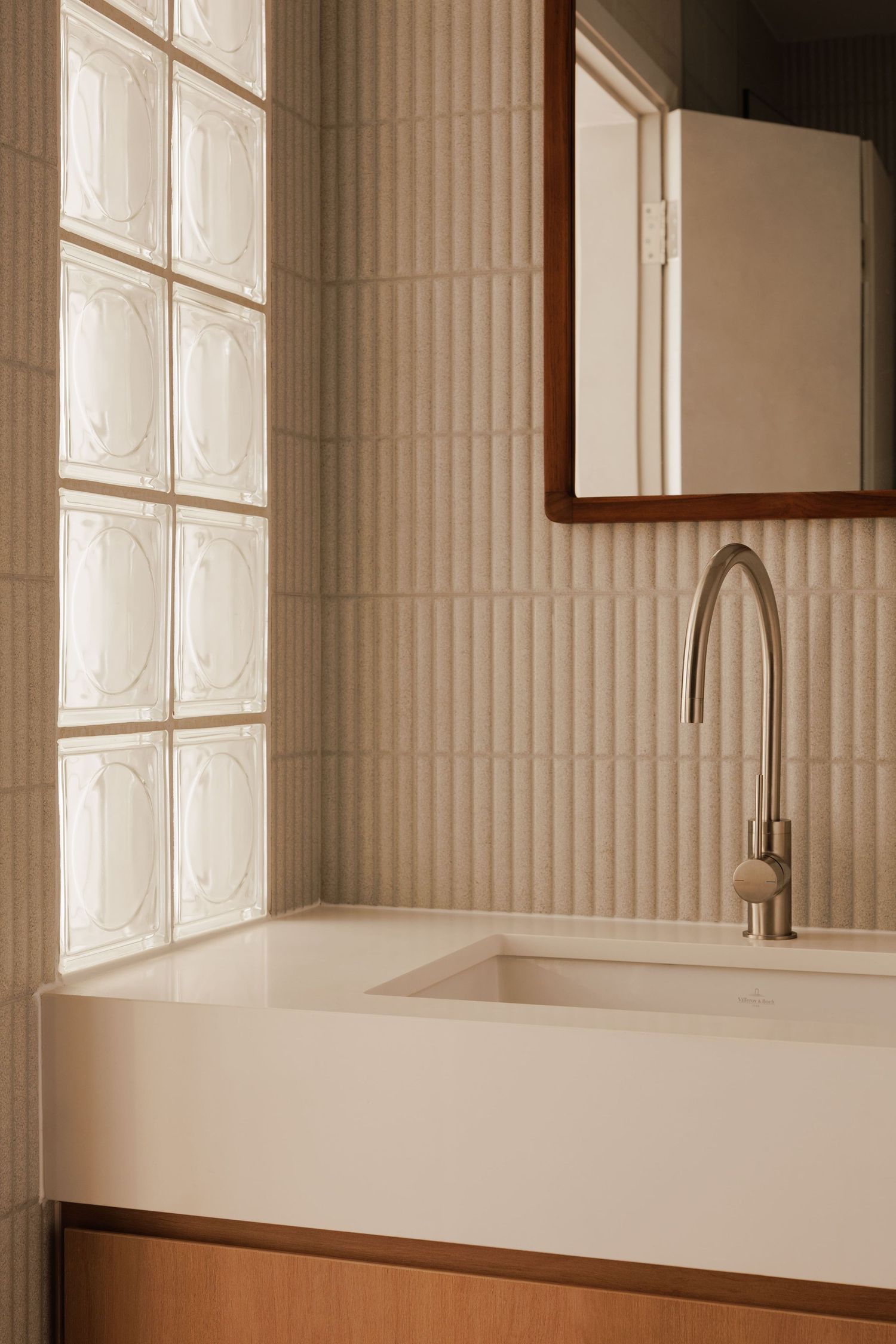 Modern white bathroom interior with glass block windows, minimalist fixtures, and sleek countertop design.