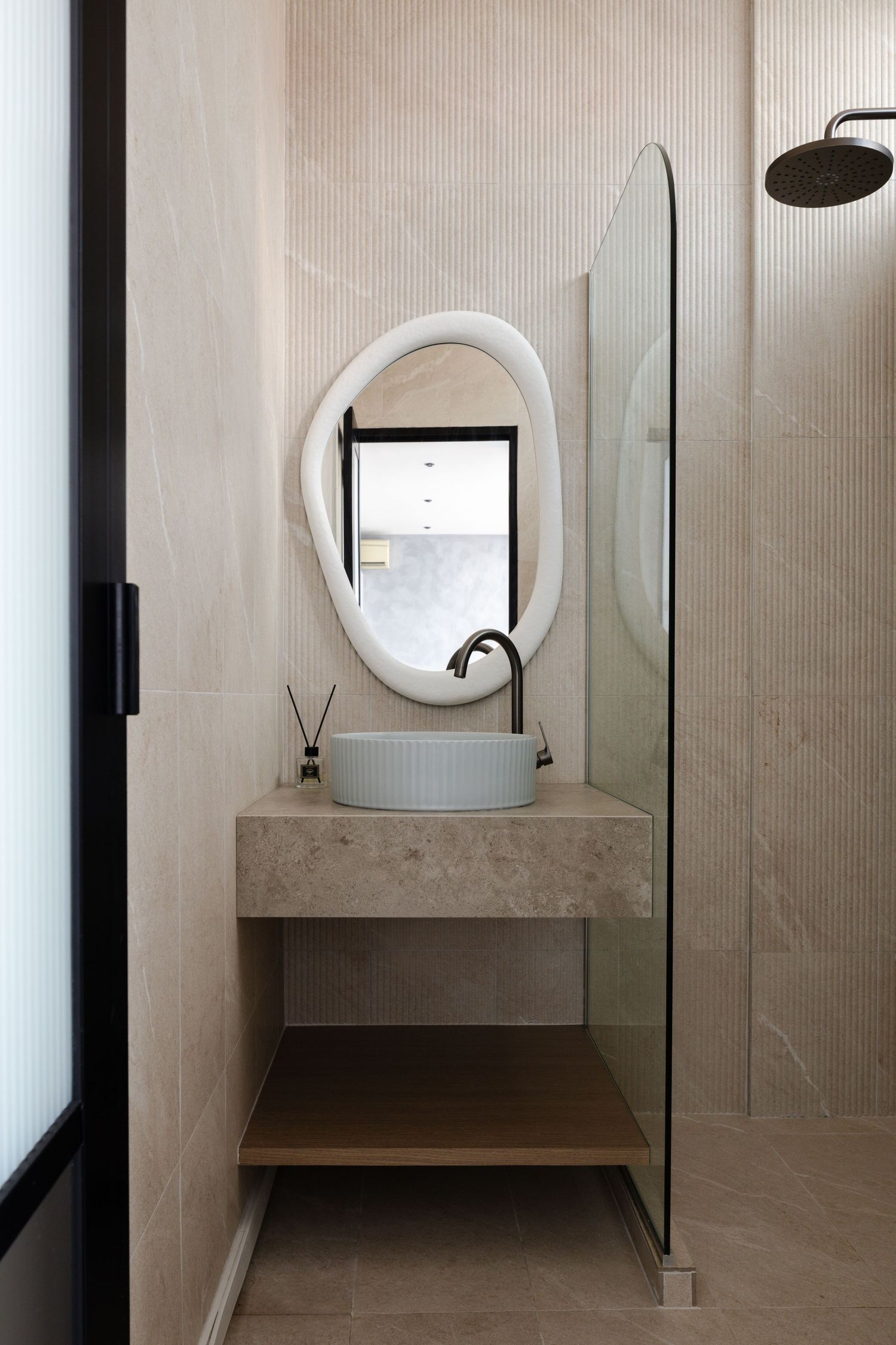 Modern minimalist bathroom with round mirror, vessel sink, and floating concrete vanity against light beige walls.