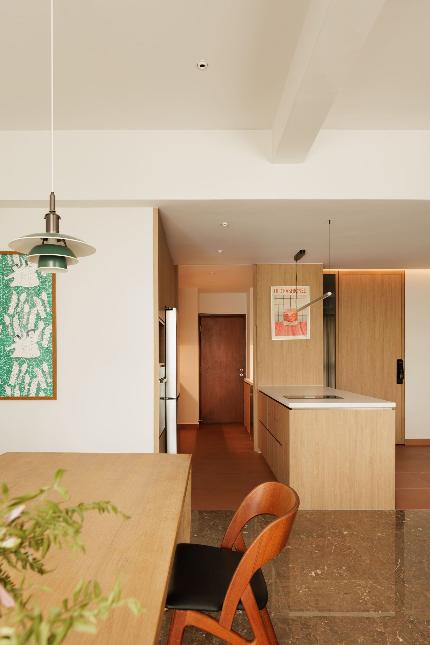 Modern apartment interior with wooden dining table, orange chair, and light wood kitchen island under pendant lighting.