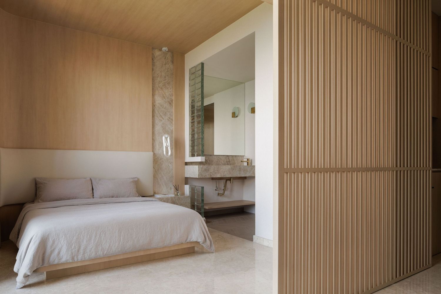 Minimalist bedroom suite features light wood paneling, white bedding, and sleek modern design elements.