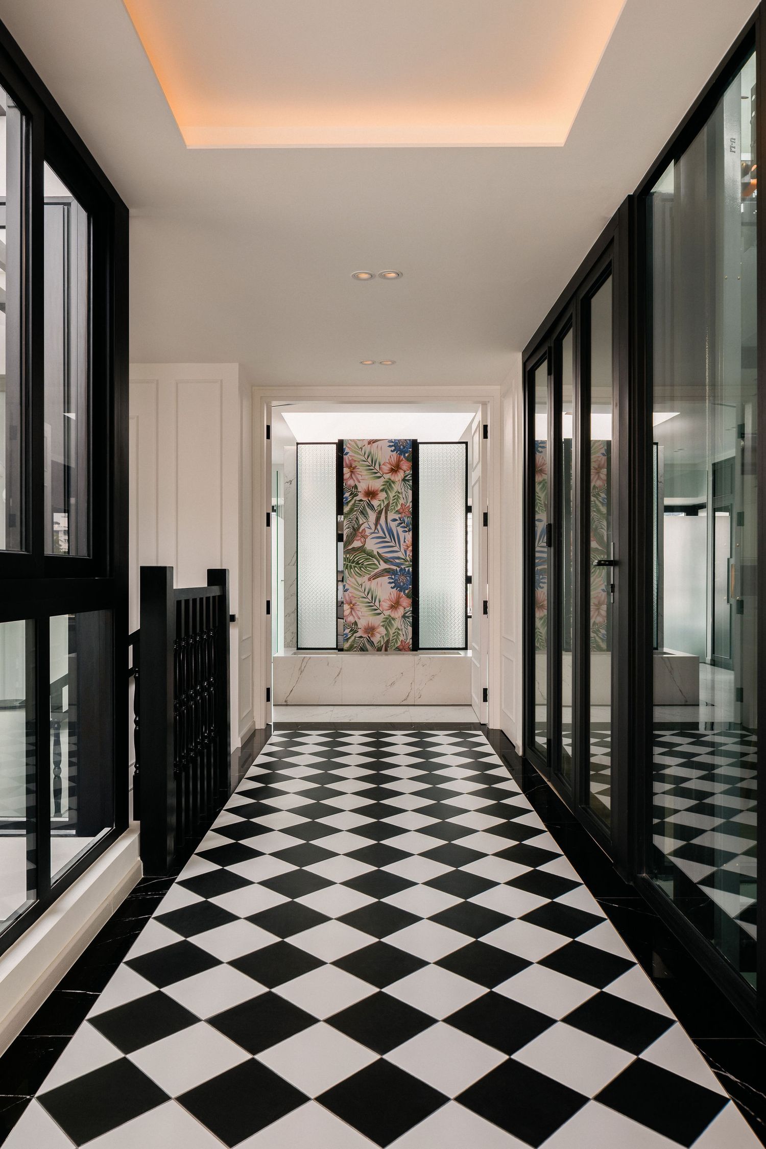 Elegant hallway with black and white checkerboard floor, black-framed glass doors, and a colorful tropical floral panel at the end.
