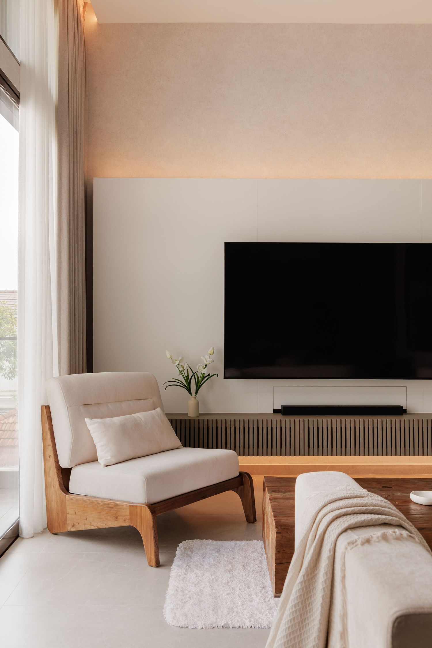 Modern minimalist living room interior with neutral tones featuring built-in wooden bench seating and black wall accents.