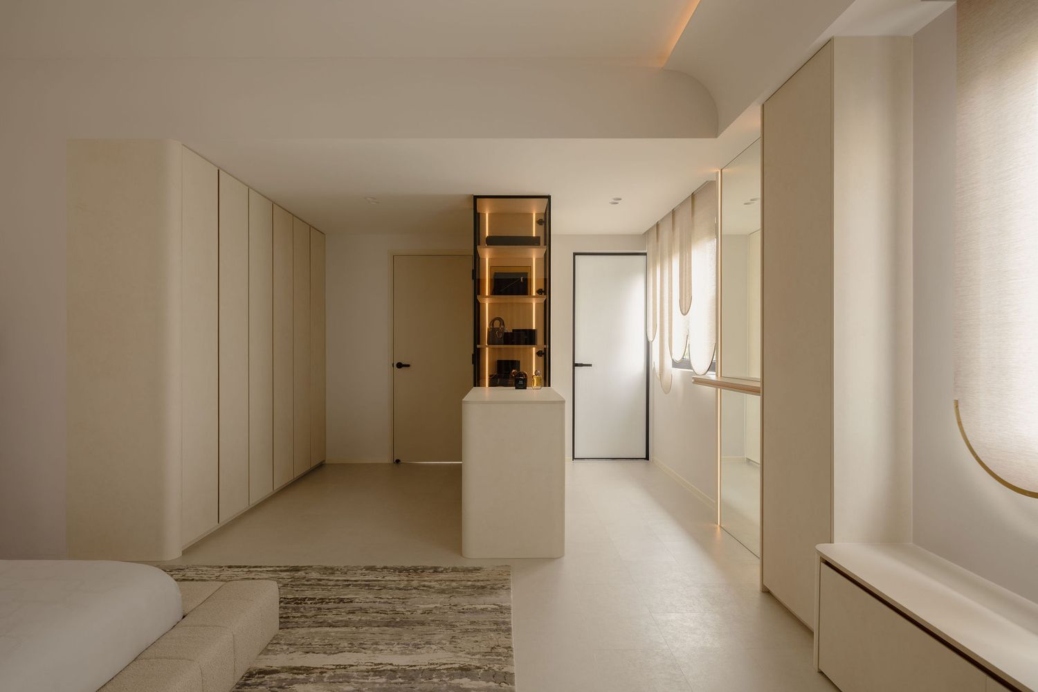 Minimalist bedroom with cream built-in wardrobes, open shelving unit, and neutral tones creating a serene, modern interior design.