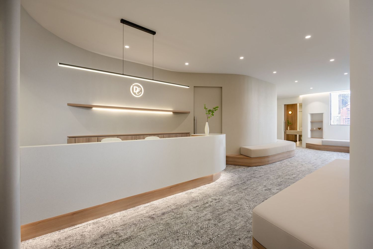 Modern minimalist office reception area with white curved desk, floating shelves, and plush grey carpet.