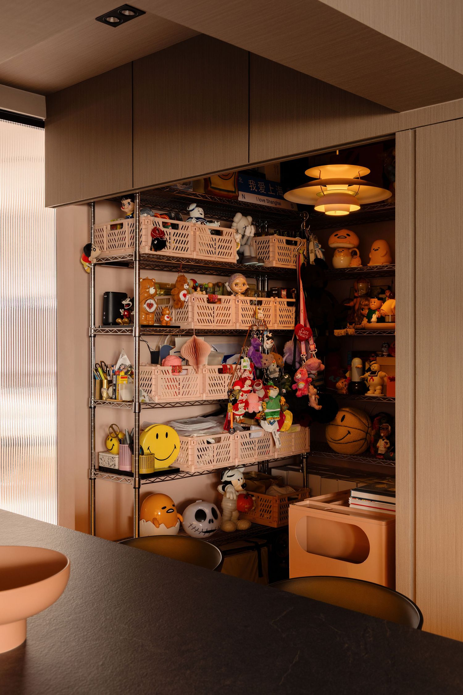 Open cabinet display shelf filled with colorful toys, stuffed animals, and wicker baskets in a modern room.