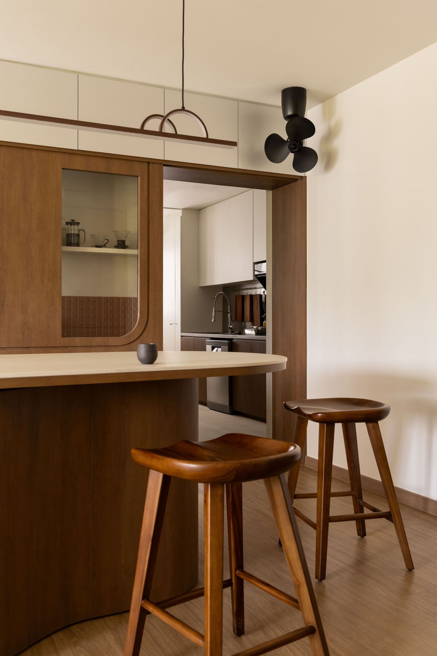 Modern wooden bar stools and built-in cabinetry create a minimalist dining space in a contemporary apartment interior.