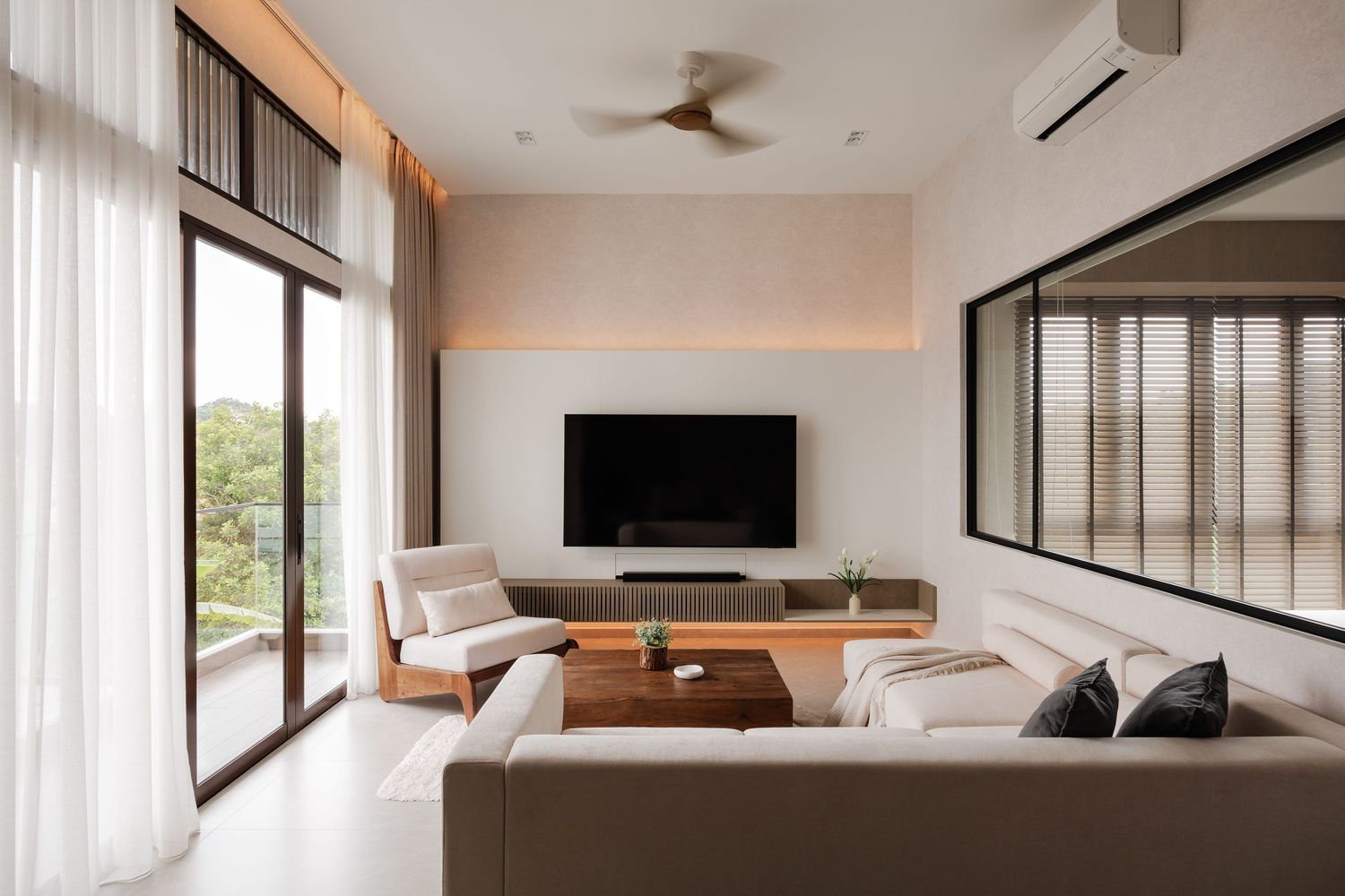 Modern open concept living room with white walls, ceiling fan, and large windows showcasing natural light.
