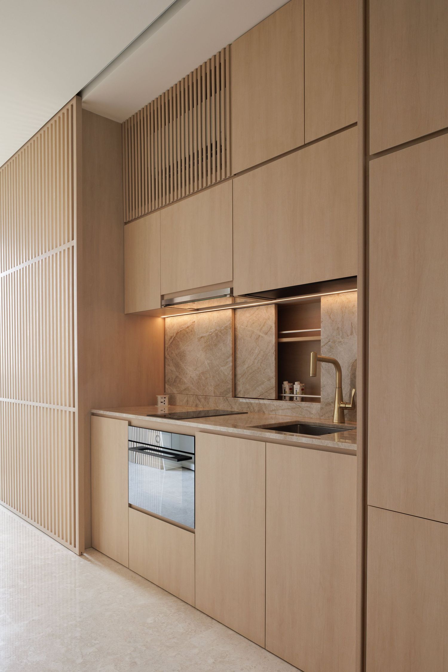 Modern minimalist kitchen with light wood cabinets, marble backsplash and hidden lighting in a sleek linear design.