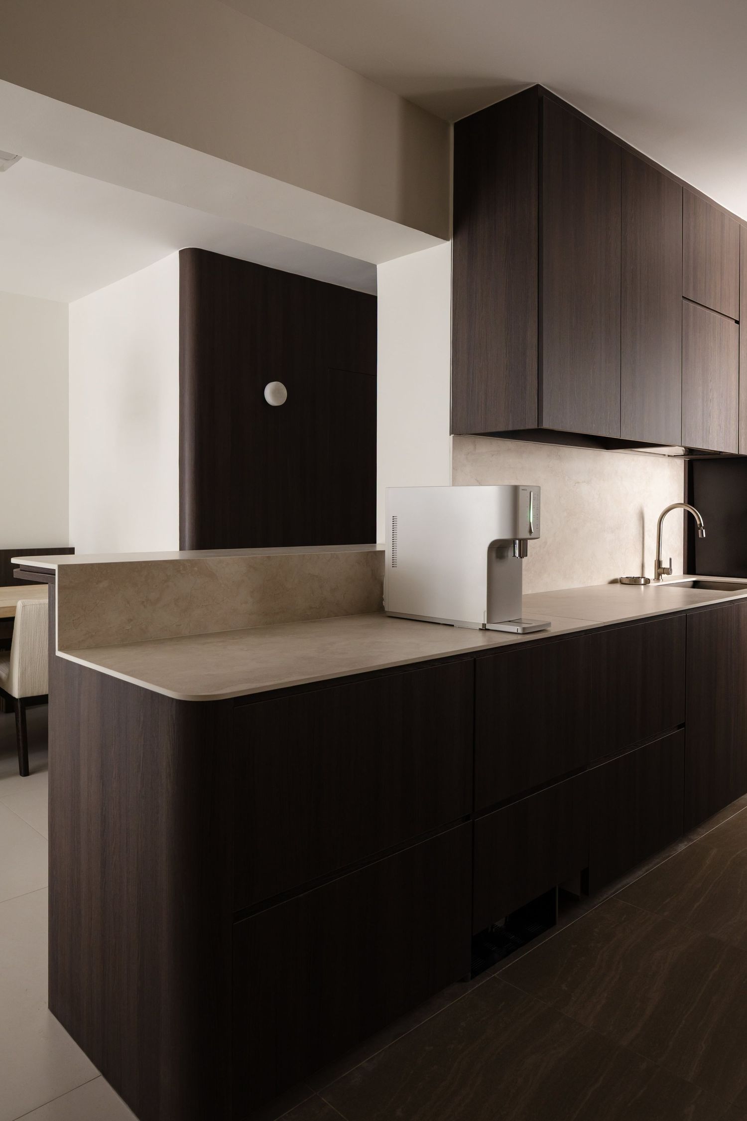 Modern kitchen design featuring sleek dark wood cabinets and white countertops with minimalist hardware and clean lines.