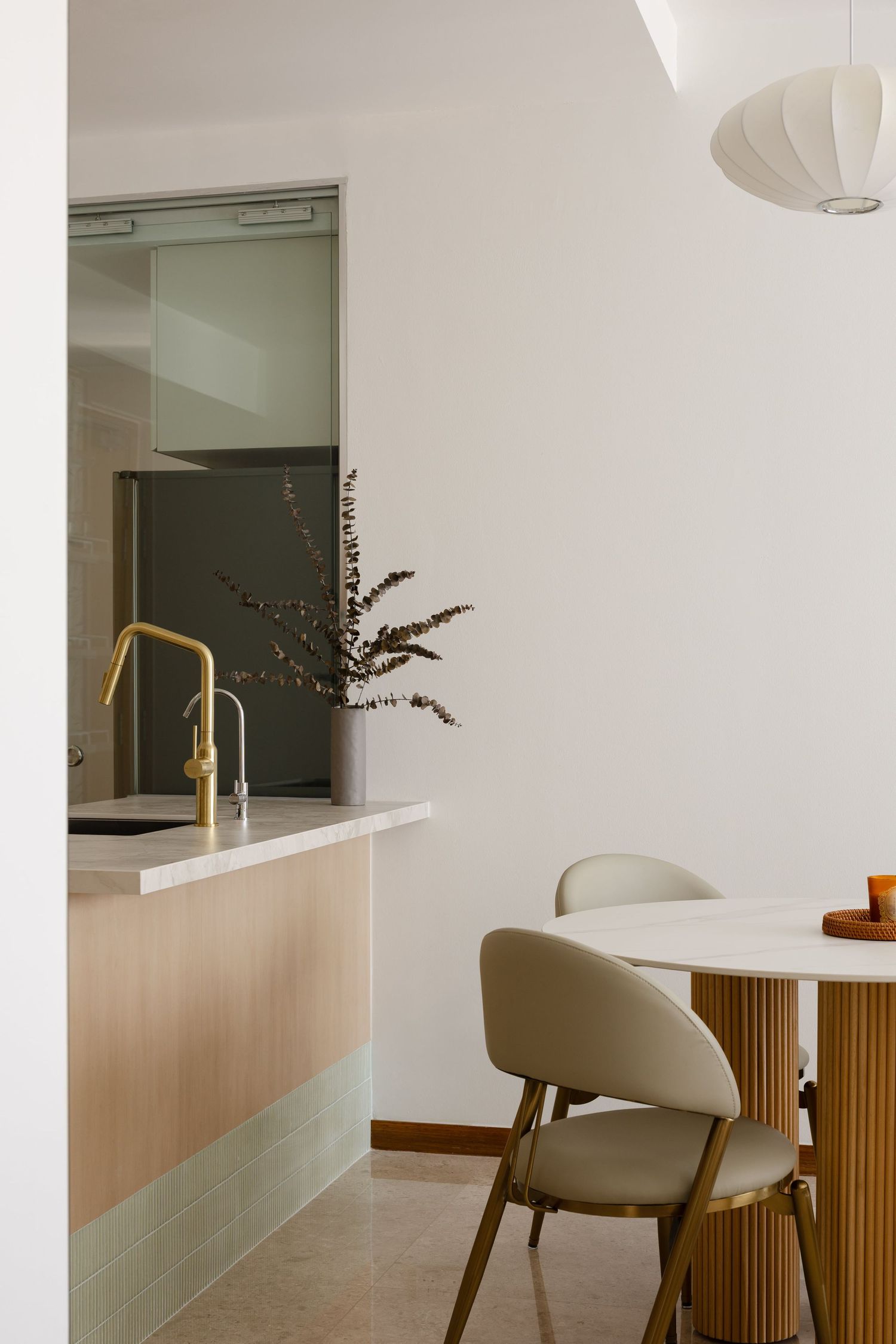 Modern minimalist dining area with light wood furniture, white chairs, and paper lantern pendant light.