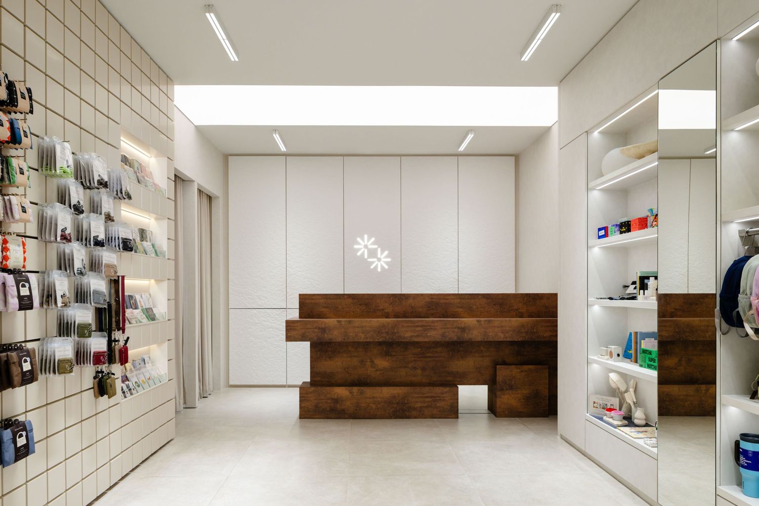 Modern retail store interior with wood reception desk, white tile walls, and sleek product display shelves.