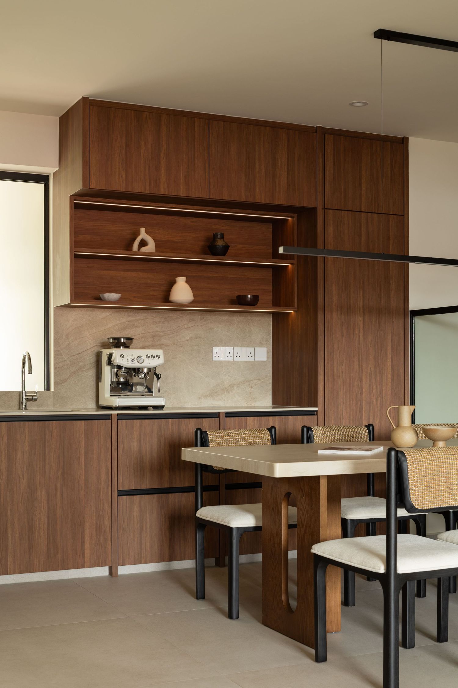 Modern office space features dark wood paneling, floating shelves, and sleek black desk frames with white countertops.