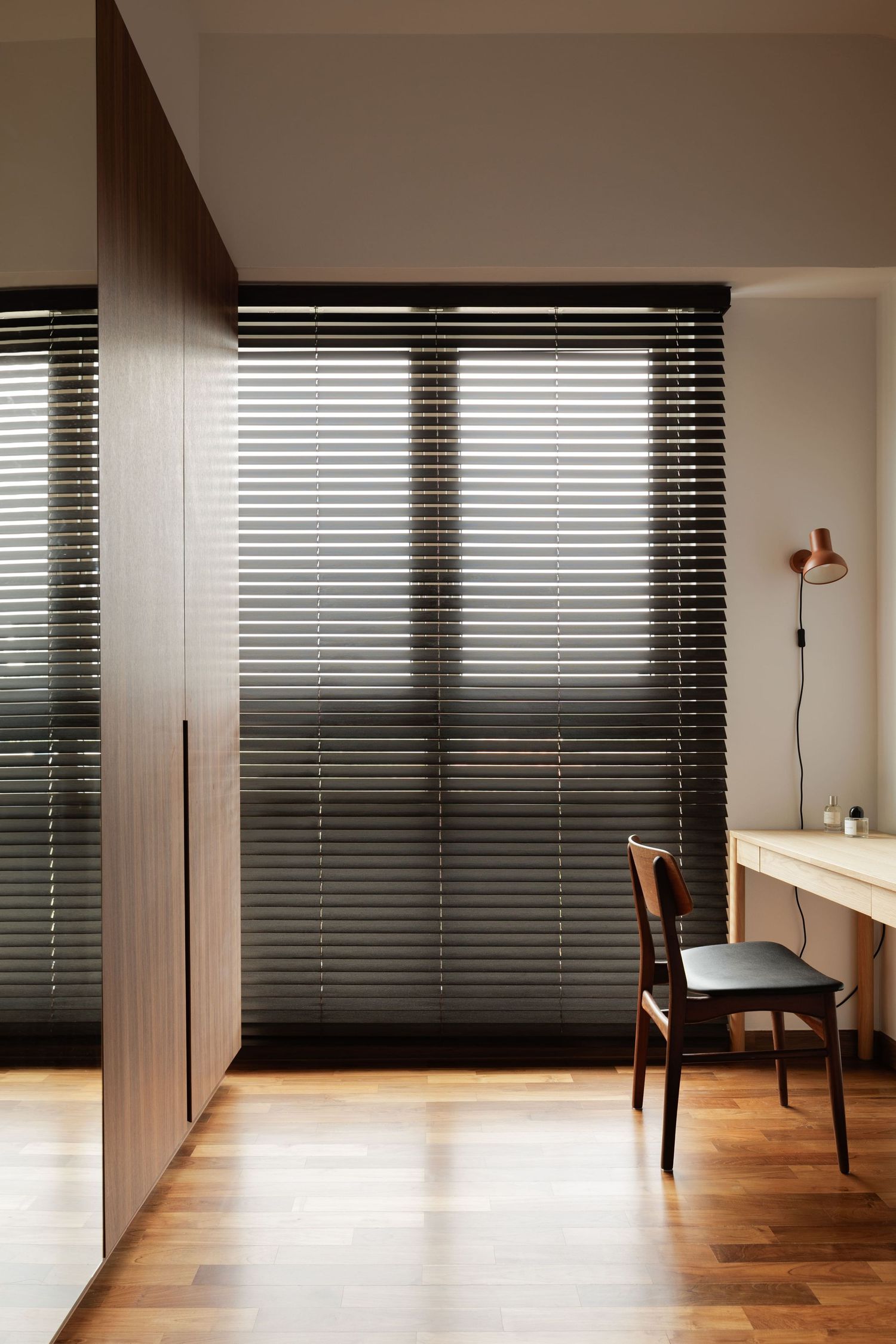 Modern room interior with dark horizontal blinds and hardwood flooring in minimalist design style.