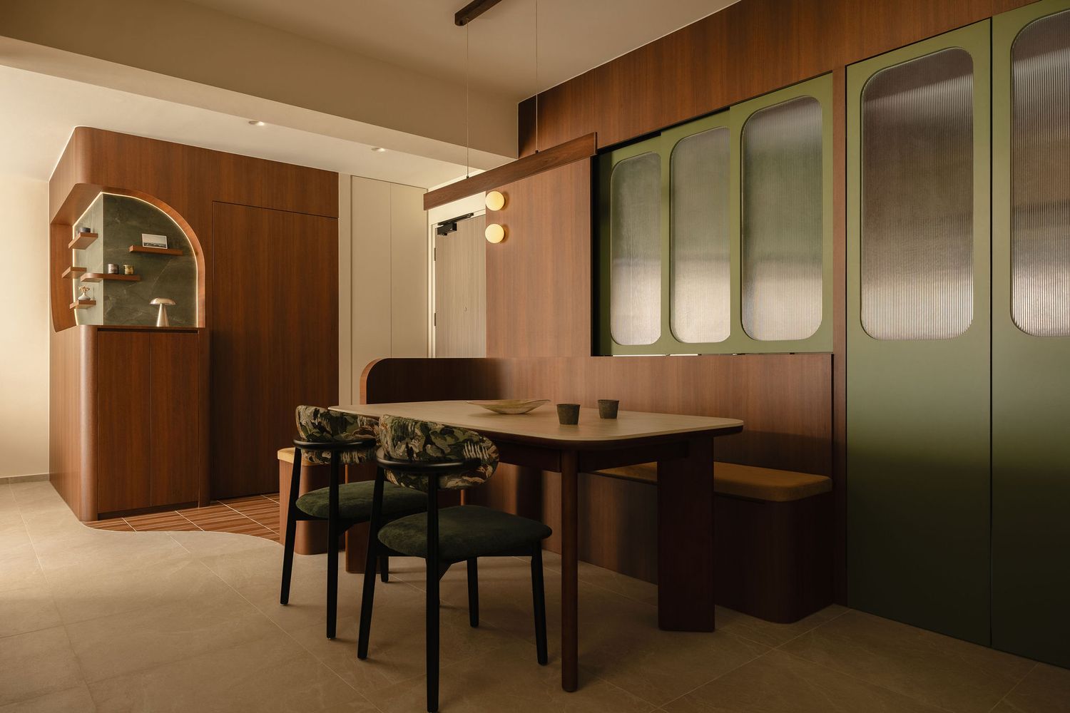Modern dining nook with a wooden table, upholstered chairs, built-in bench, green fluted-glass cabinets and warm walnut paneling.