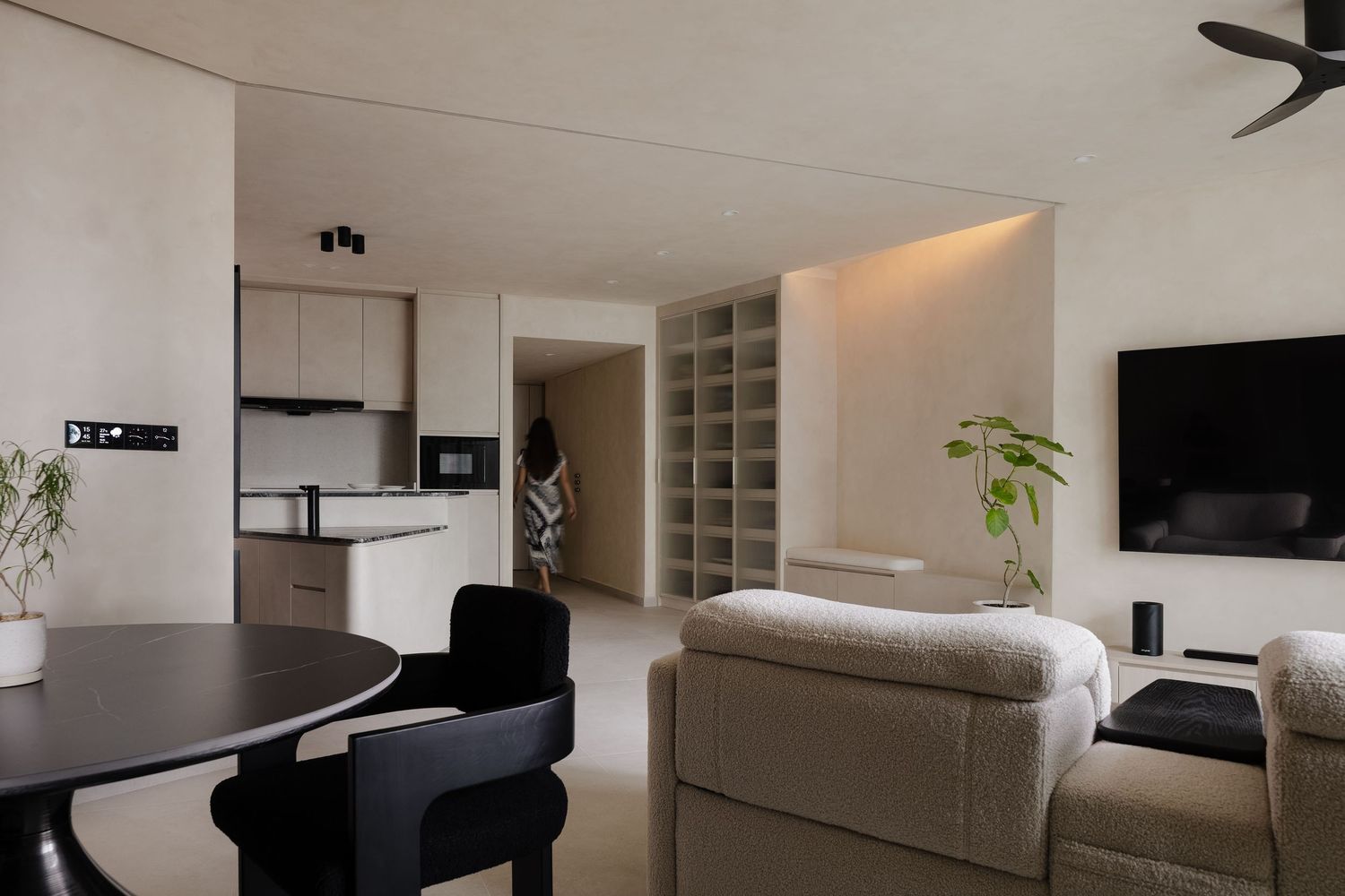 Modern minimalist living room with white walls, built-in shelving, and sleek black and white furniture design.