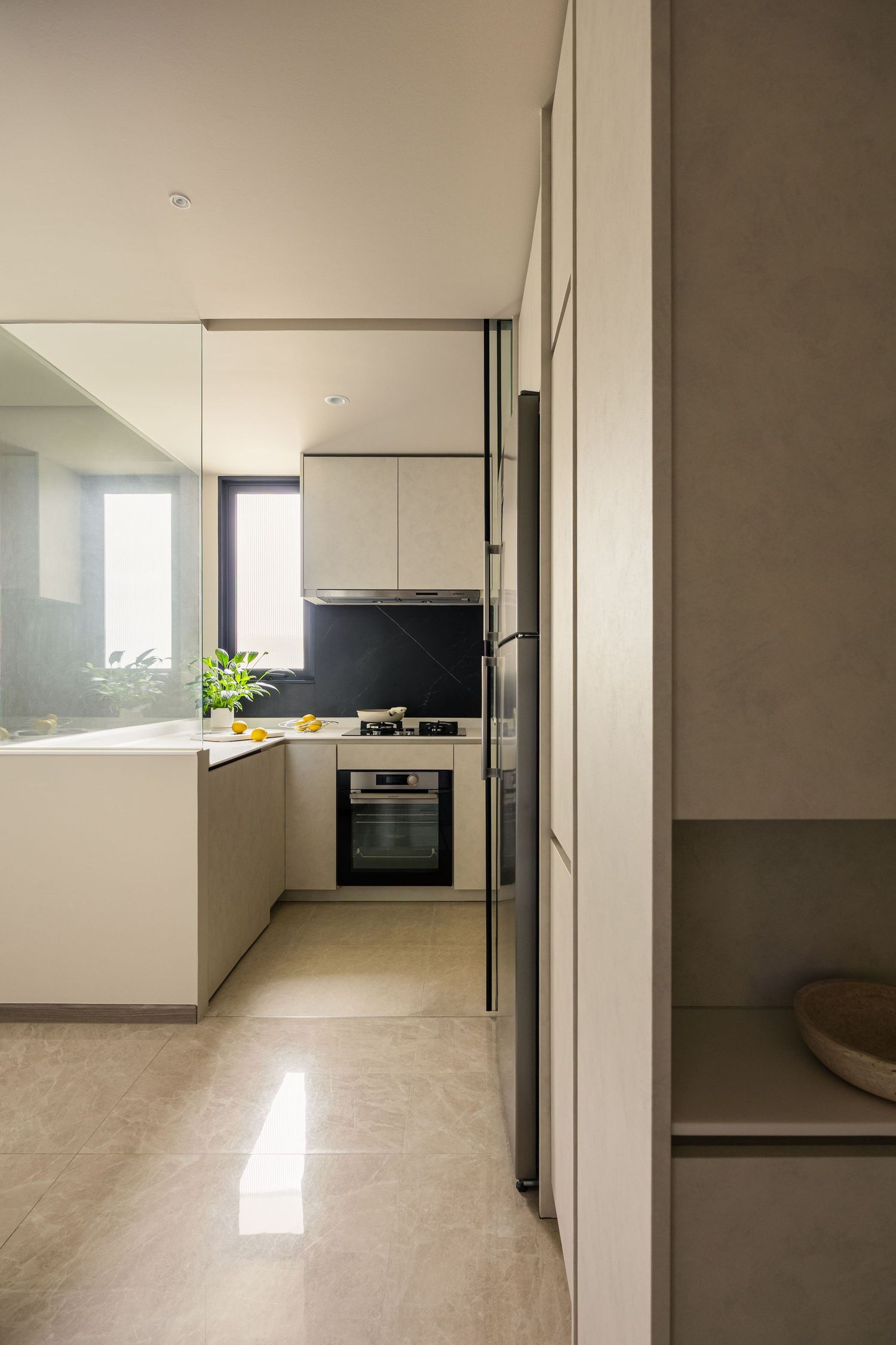 Modern minimalist kitchen with white cabinetry, stainless steel appliances, black backsplash, and glossy beige tile flooring.